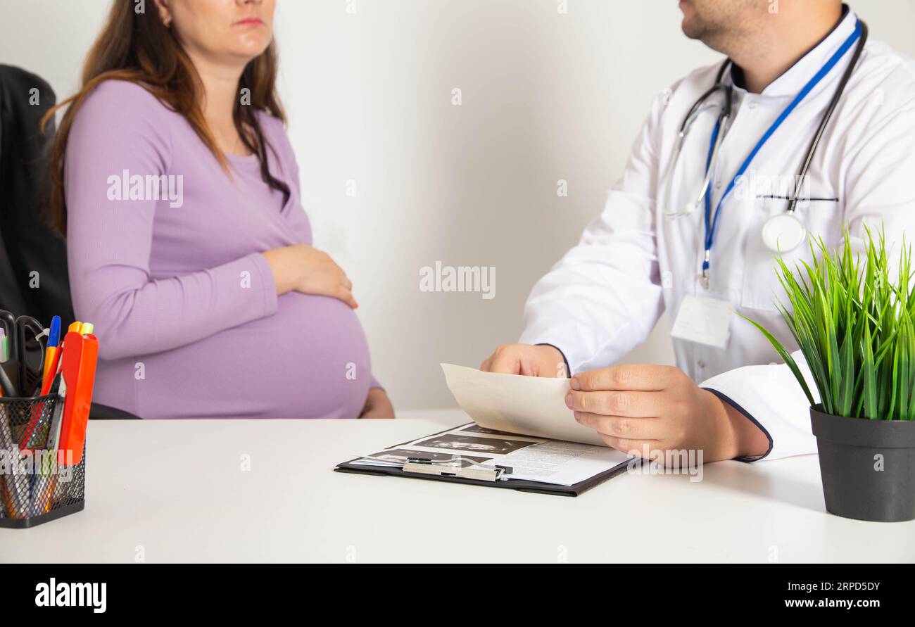 Schwangere Frau in der Arztpraxis. Schwangerschaftserhaltung bei Frühgeburt und Bauchschmerzen. Stockfoto