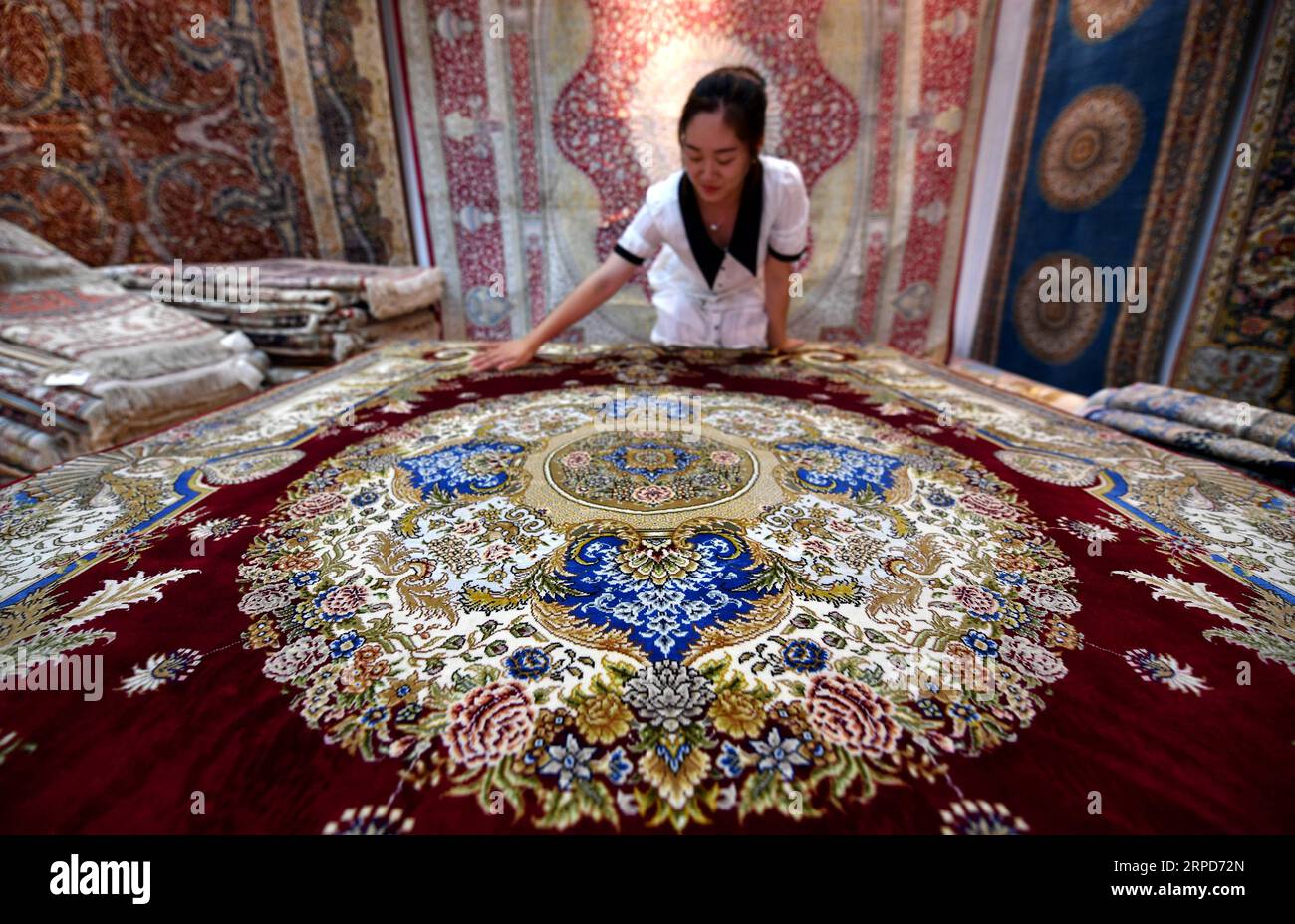 (190725) -- ZHENGZHOU, 25. Juli 2019 -- Ein Arbeiter von Yuxiang Carpet arrangiert einen Seidenteppich in Nanyang, zentralchinesische Provinz Henan, 17. Juli 2019. Während handgenähte iranische Teppiche weltweit für ihre exquisite Handwerkskunst bekannt sind, ist eine wenig bekannte Tatsache, dass eine Stadt in Zentralchina etwa 5.000 km entfernt einst etwa 80 Prozent aller handgefertigten Seidenteppiche produzierte, die weltweit verkauft wurden. 29 aufwändig gewebte, handgenähte Teppiche im persischen Stil werden derzeit in einem Lager im Nanzhao County in der Stadt Nanyang, der zentralchinesischen Provinz Henan, gerollt und verpackt. Sie werden sich bald einsperren Stockfoto