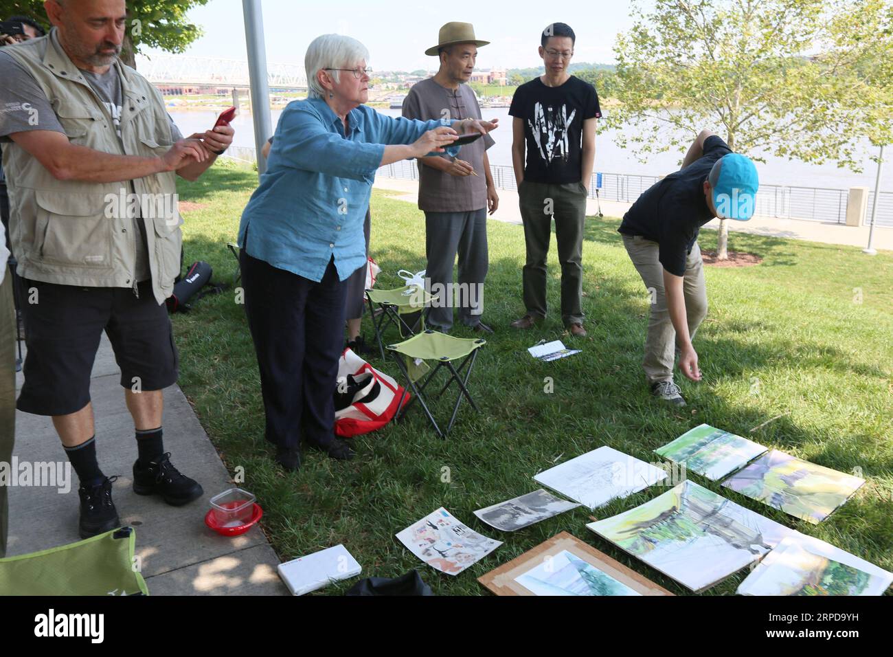 (190727) -- CINCINNATI (USA), 27. Juli 2019 -- Jan Brown Checco (2. L), Lead Artist des Cincinnati/Liuzhou Paint Out Program, fotografiert die Zeichnungen mit ihrem Handy im Smale Riverfront Park in Cincinnati, Ohio, USA, 25. Juli 2019. Chinesische und US-amerikanische Künstler nahmen kürzlich am Cincinnati/Liuzhou Paint Out Program Teil, bei dem Künstler aus der südchinesischen autonomen Region Guangxi Zhuang eingeladen wurden, Cincinnati für eine Woche zu besuchen. Sie besuchten Museen und Galerien, tauschten sich mit ihren US-amerikanischen Kollegen über Kunstauffassungen und -Techniken aus und präsentierten ein gemeinsames Exhib Stockfoto