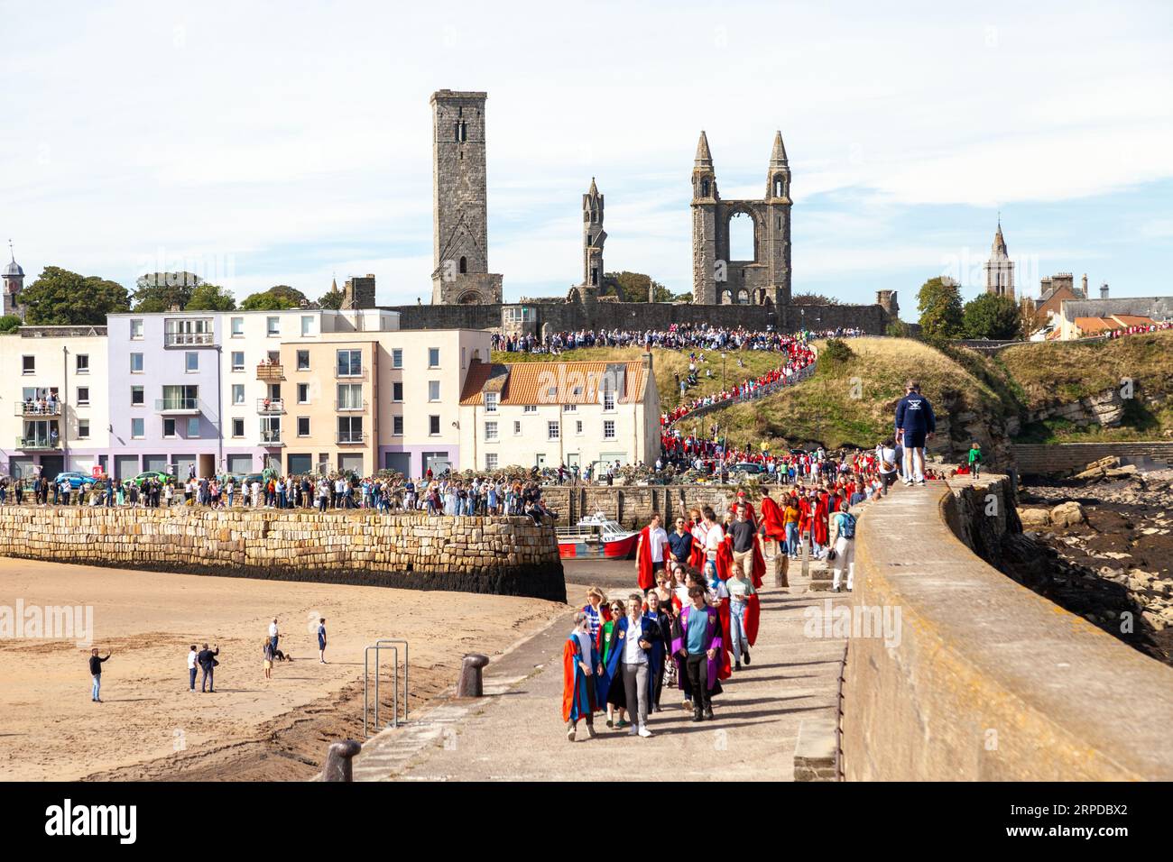 Neue Studenten der Universität von St. Andrews in roten Gewändern nehmen an der traditionellen Pier Walk entlang der Hafenmauern von St. Andrews Teil Stockfoto