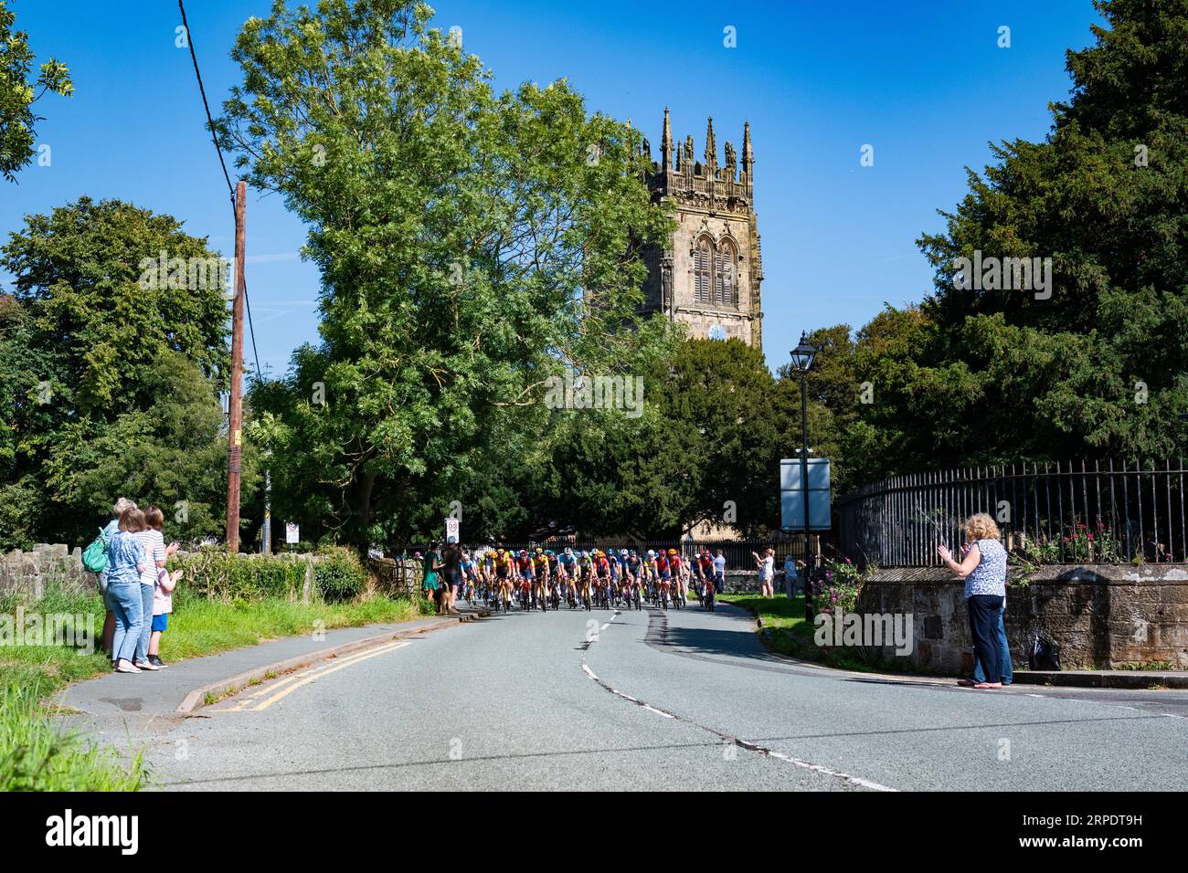 Szenen von Leg 2 der Tour of Britain, Wrexham bis Wrexham, während das Peleton eines der 7 Wonders of Wales, Gresfords All Saints Church, passiert. Stockfoto