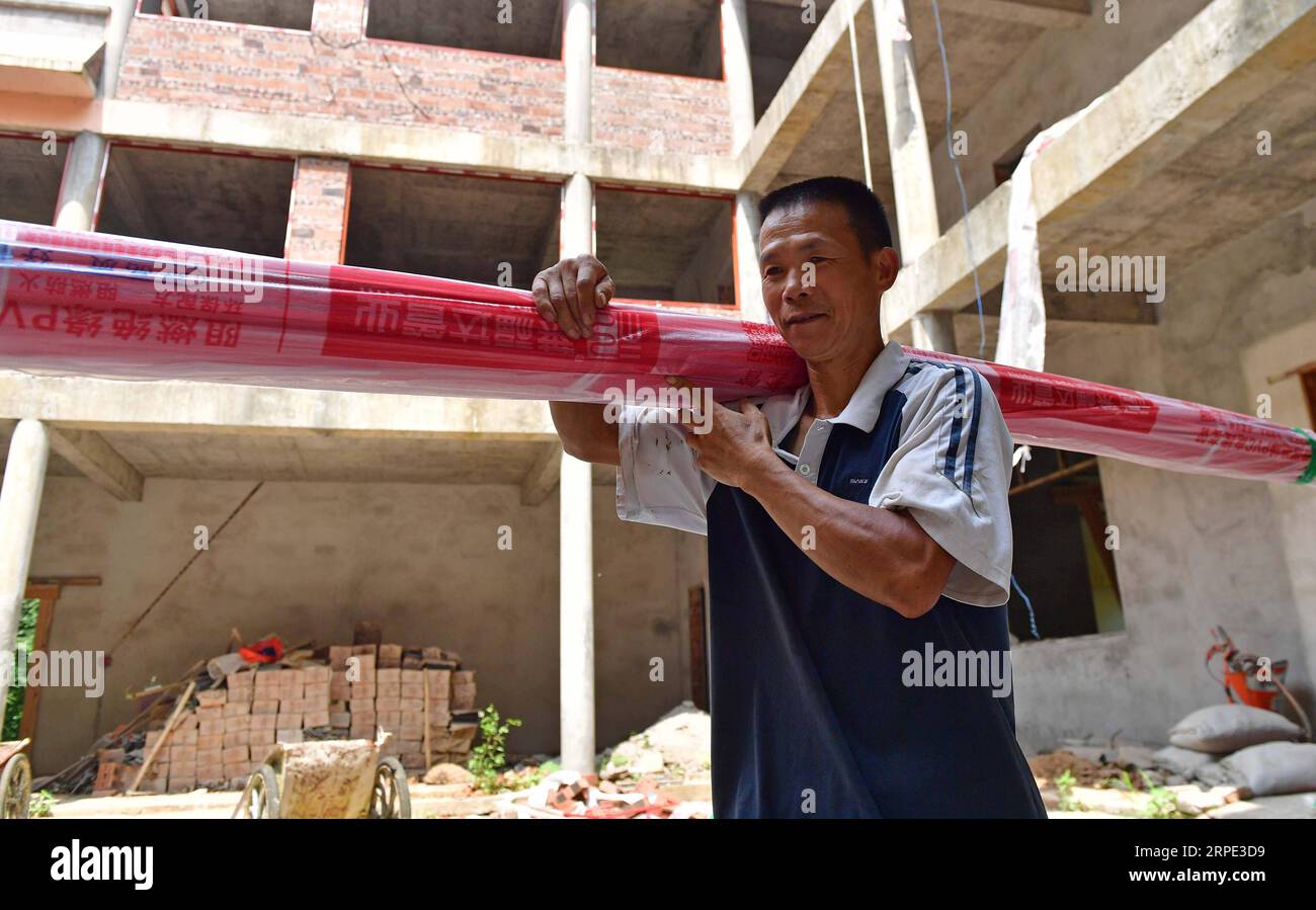 (190816) -- RONGSHUI, 16. August 2019 -- Long Gexiong trägt Materialien für die Hausdekoration im Dorf Tongbantun der Gemeinde Dongqi im Bezirk Rongan, südchinesische autonome Region Guangxi Zhuang, 16. August 2019. Long Gexiong, ein 51-jähriger Bauer des Dorfes Tongbantun, der 20 Jahre lang Wanderarbeiter war, kehrte 2012 in seine Heimatstadt zurück, um mit seinen Cousins eine Bauerngenossenschaft für Obstverkauf und Landtourismus zu gründen. Lange und andere Landwirte haben Pflaumenbäume und Trauben auf einer Gesamtfläche von mehr als 500 Mu (etwa 33,33 Hektar) gepflanzt und die Anstrengungen zur Entwicklung der Tourismusbranche intensiviert Stockfoto