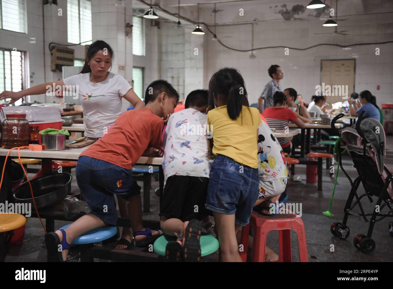 (190818) -- PEKING, 18. August 2019 -- Lu Changli (4. L) und ihr Bruder Lu Penghan (5. L) sehen sich einen Cartoon mit anderen Kindern in der Kantine einer Kleiderfabrik in Shishi, südöstliche Provinz Fujian, 1. August 2019 an. Die sengende Hitze hat Shishi im Südosten Chinas Fujian in diesem Sommer verschlingen lassen und nur wenige laufen auf den normalerweise geschäftigen Straßen. Im Gegensatz dazu sind die Kleiderfabriken, die in der Stadt dicht besiedelt sind, mit Menschen überfüllt, die von ihrer Arbeit überschwemmt wurden, da der Sommer die Hauptsaison für die Herstellung von Kleidungsstücken jedes Jahr ist, und auch ihre Kinder. T Stockfoto