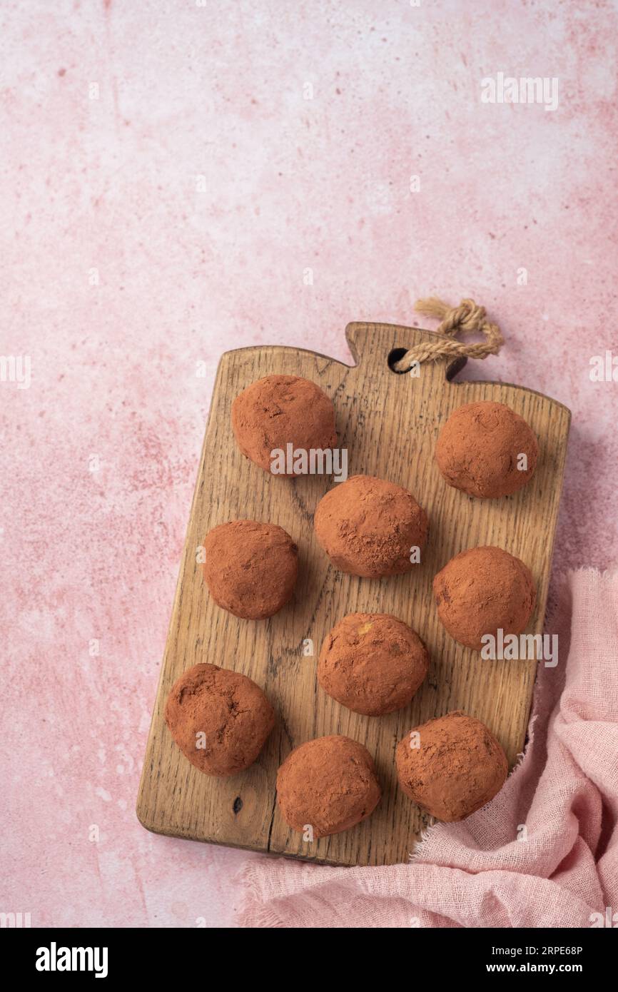 Schokoladentrüffel mit Kakaopulver bedeckt. Rosafarbener Hintergrund. Tabelle mit Draufsicht. Leckere Süßigkeiten, leckeres Dessert. Stockfoto