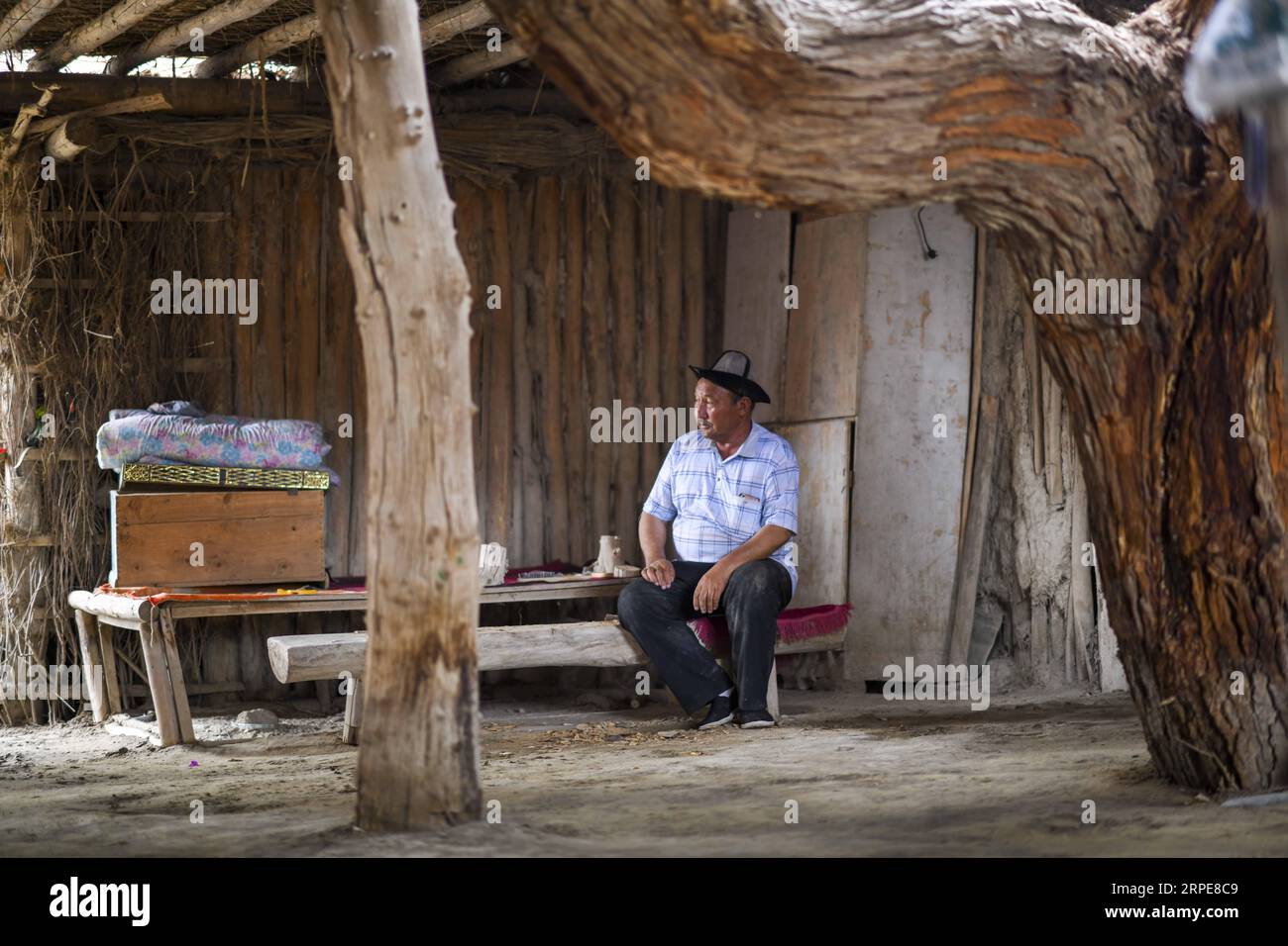 (190821) -- YULI, 21. August 2019 -- Amudun Abudu liegt zu Hause im Dorf Lop nur im Yuli County, nordwestchinesische Autonome Region Xinjiang Uygur, 21. Juni 2019. Lop nur People Village liegt im Yuli County, wo der Tarim River durch die Wüsten fließt, wobei die Populus euphratica Wälder die schimmernden Wellen reflektieren. Amudun Abudu, ein 61 Jahre alter typischer Dorfbewohner von Lop nur, arbeitet in der lokalen Tourismusbranche. Mit dem Wandel der Zeit haben viele Menschen in Lop nur verschiedene Lebensmöglichkeiten, doch er beharrt auf der Tradition des Fischens in Flüssen und Seen. Er macht nicht nur Deliciou Stockfoto