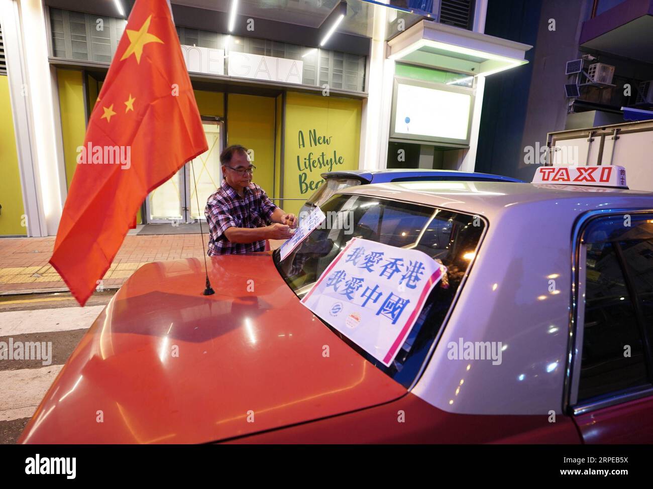 (190824) -- HONG KONG, 24. August 2019 -- Ein Mann hängt Poster mit der Aufschrift I Love Hong Kong an. Ich liebe China. Zu einem Taxi während einer friedlichen Kundgebung in Hongkong, Südchina, 23. August 2019. Fast 600 Taxis nahmen am Freitag an einer Friedensdemonstration gegen Gewalt Teil und zeigten den Einwohnern Hongkongs die Liebe zu ihrem Zuhause und dem Mutterland. Die von der Bürgergruppe Safeguard Hong Kong and Hong Kong Taxi Drivers and Operators Association organisierte Kundgebung zielte darauf ab, die Hongkonger Gemeinschaft zu drängen, sich gemeinsam gegen Gewalt zu stellen und die soziale Ordnung so schnell wie möglich wiederherzustellen, so die Organisatoren. CHINA-HONGKONG-TAXIS RA Stockfoto
