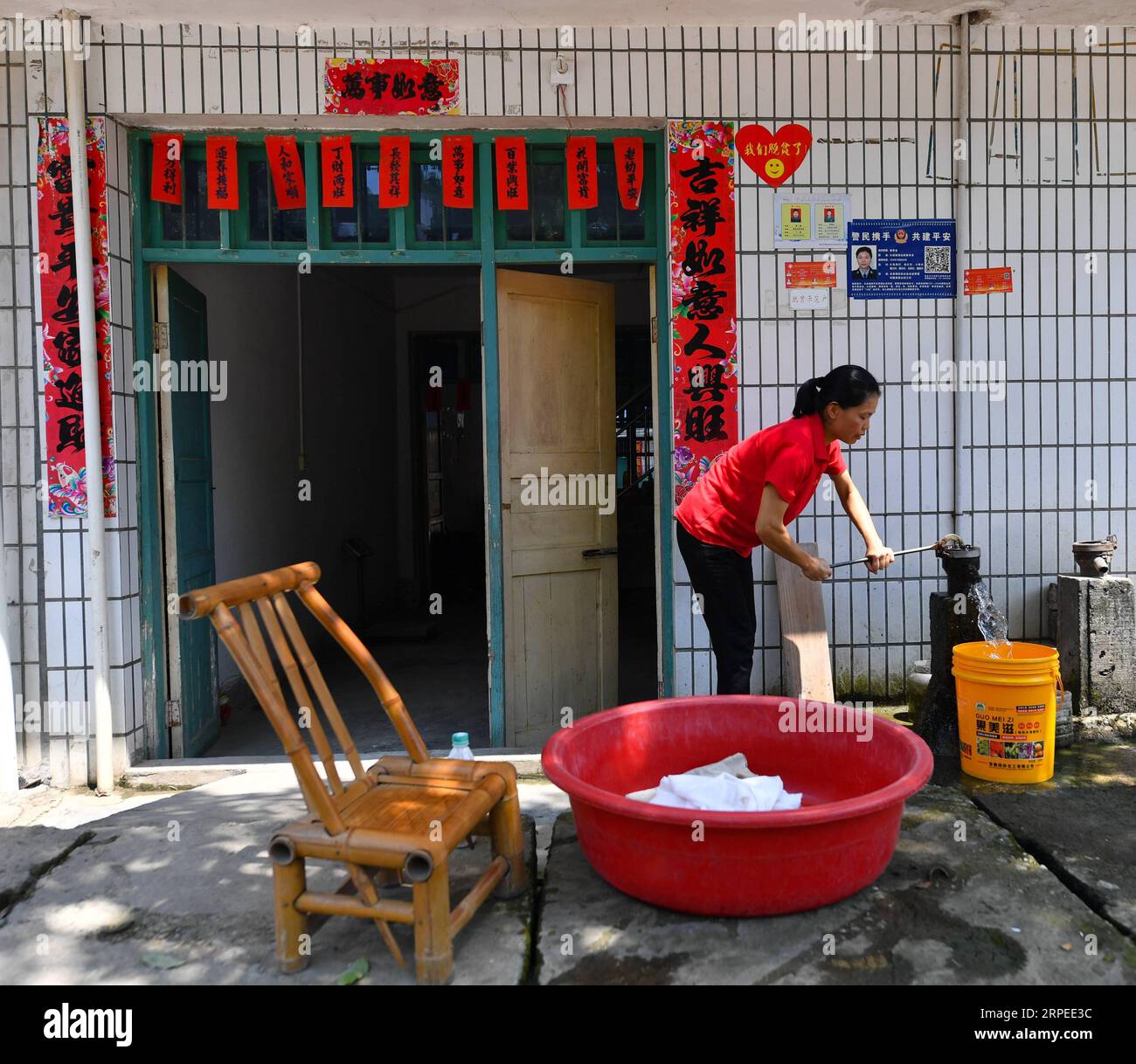 (190826) -- NANCHANG, 26. August 2019 -- Liu Lihong holt Wasser, um Kleidung zu Hause in der Gemeinde Dabaidi der Stadt Ruijin, ostchinesische Provinz Jiangxi, 19. August 2019 zu waschen. Liu Lihong trägt eine schwarze Baskenmütze und ein Paar High-Heels und frittiert Fleisch und Gemüse in Kochherden, während sie Musik hört, eine typische Szene in ihrer täglichen Routine. Der 40-jährige Koch arbeitet seit drei Jahren für die lokale Regierung der Gemeinde Dabaidi. Vor seiner Tätigkeit als professioneller Koch war Liu seit seinem 19. Lebensjahr Wanderarbeiter in einer Bekleidungsfabrik in Shantou in der südchinesischen Provinz Guangdong Stockfoto
