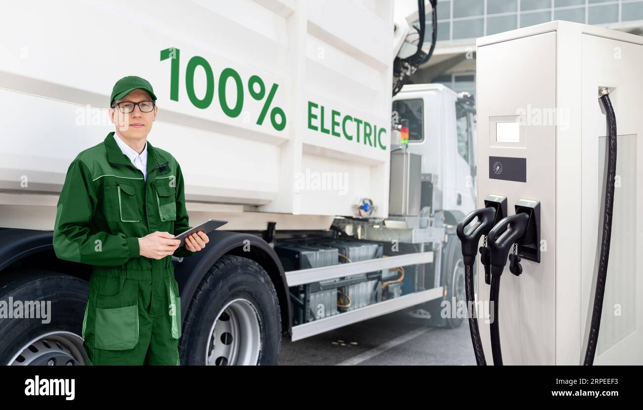 Manager mit einem digitalen Tablet neben Elektro-Müllwagen und ekektrischer Fahrzeugladestation. Stockfoto