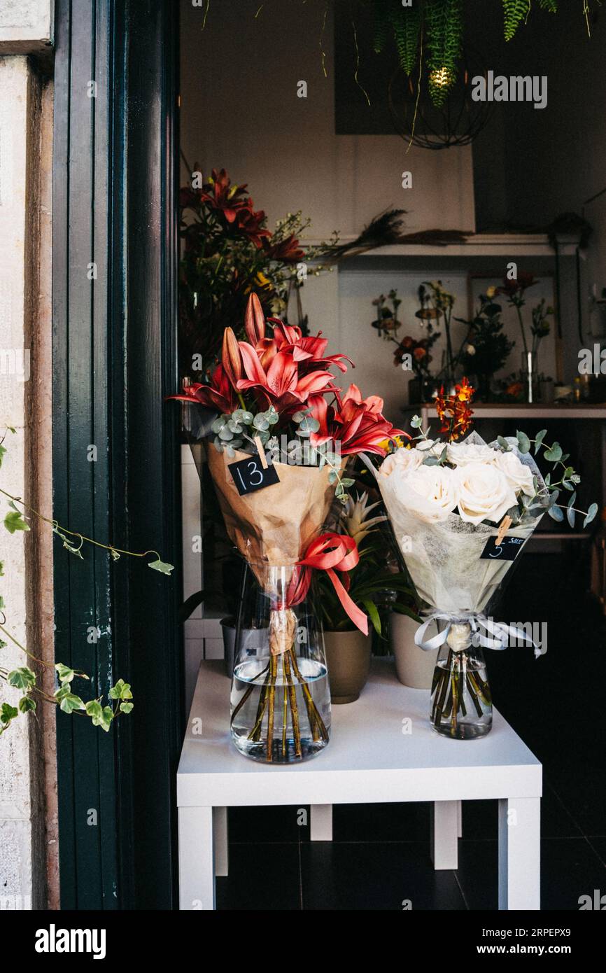 Verschiedene schöne Blumensträuße mit gemischten Blumen auf weißem Tisch am Eingang zum Laden, im Fenster. Blumengeschäft-Konzept. Leerzeichen kopieren Stockfoto