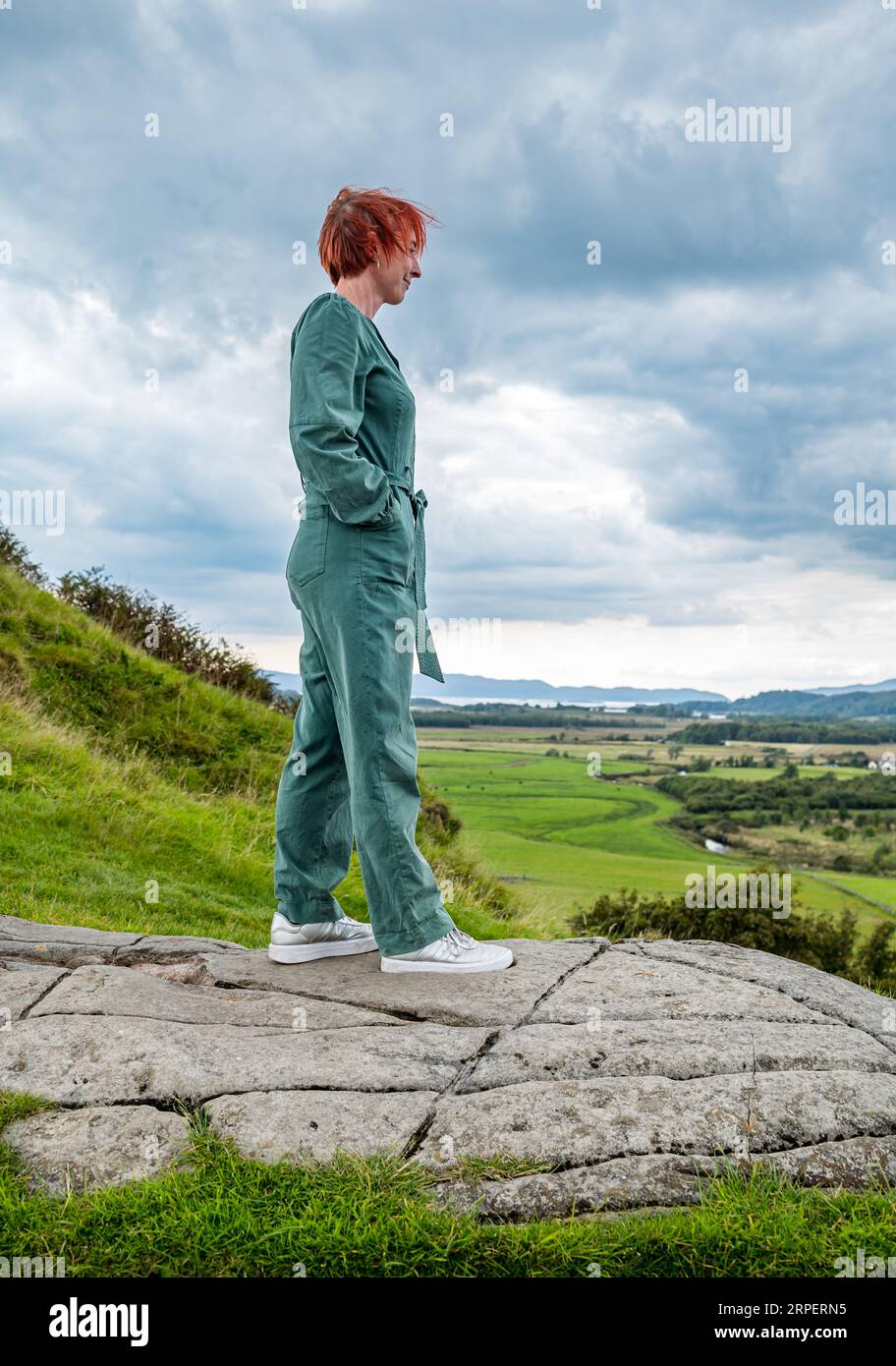 Frau, die in Fels steht, Dunadd Hill Fort, Kilmartin Glen, Argyll, Schottland, UK Stockfoto