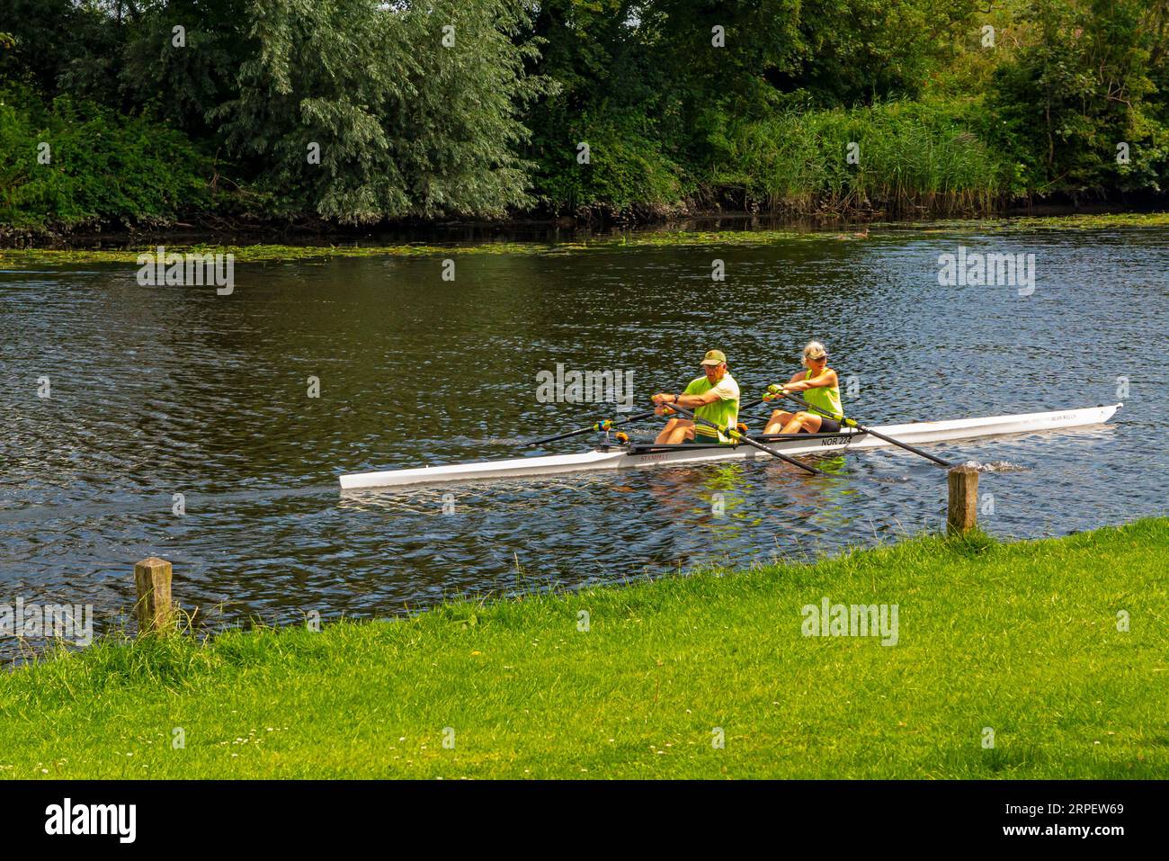 Ein Paar rudert ein Boot auf dem Fluss Yare in Bramerton Common in den Norfolk Broads England. Stockfoto