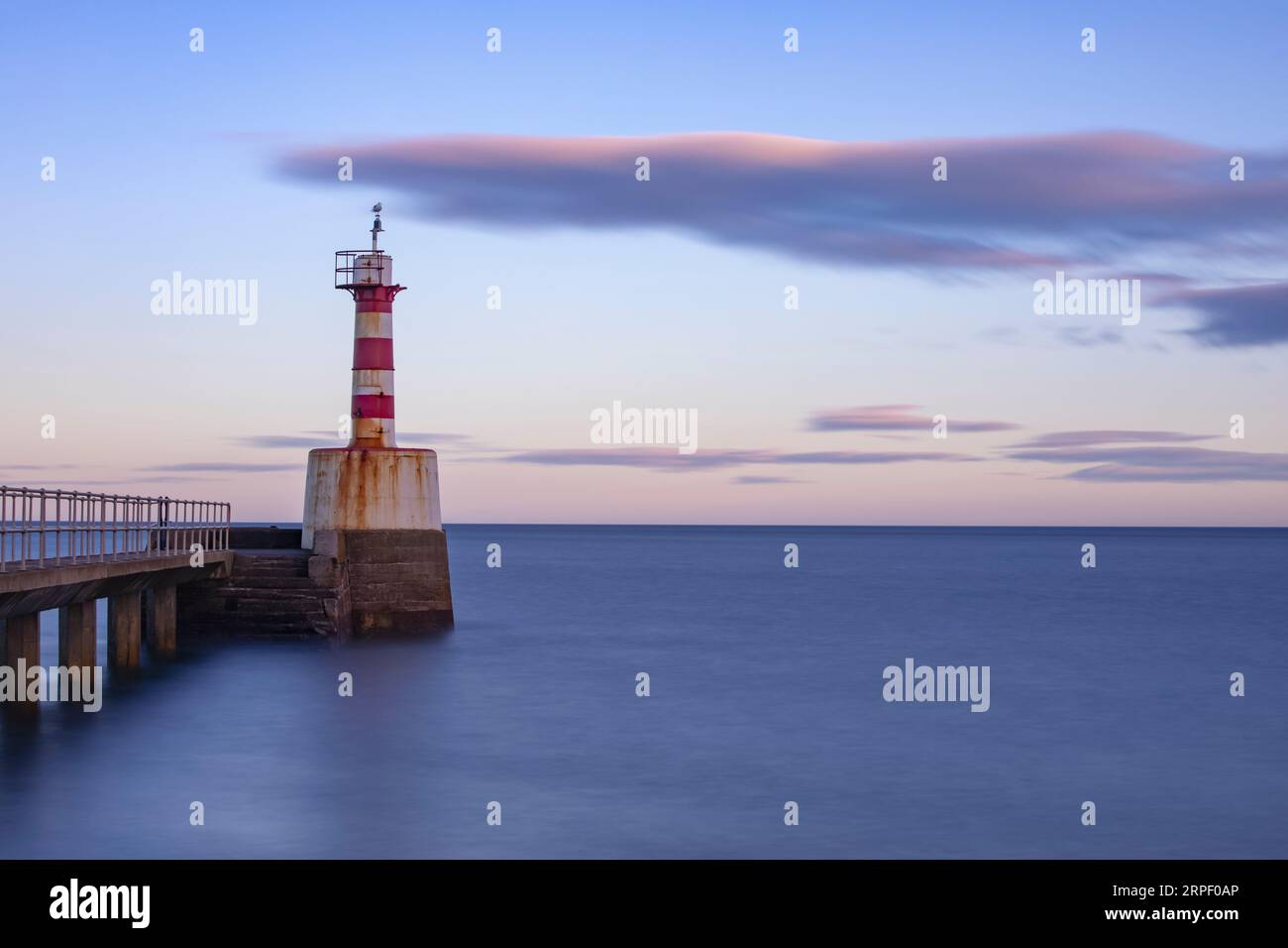 Langzeitbelichtung des South Jetty und Lighthouse bei Sonnenuntergang im November. Amble, Northumberland, Northumberland Coast, Großbritannien Stockfoto