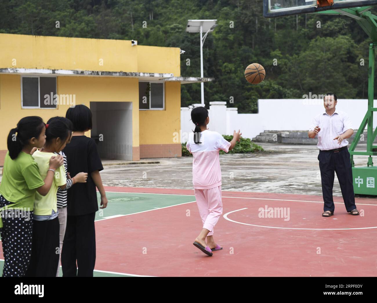 (190908) -- TIANDONG, 8. September 2019 -- Wei Guoji spielt Basketball mit Schülern an der Tuogua Primary School im Dorf Tuogua im Zuodeng Yao Ethnic Township des Tiandong County, südchinesische Autonome Region Guangxi Zhuang, 3. September 2019. Die Grundschule Tuogua liegt in abgelegenen Bergen des Tiandong County und ist mehr als 60 km vom County Seat entfernt, zu dem nur eine schroffe Bergstraße führen kann. Der 53-jährige Wei Guoji, ein gebürtiger Bewohner des Dorfes, ist der Direktor der Dorfschule. Wei wurde als Ersatzlehrer der Schule nach dem Abschluss der Mittelschule im Alter von 18 Jahren rekrutiert Stockfoto