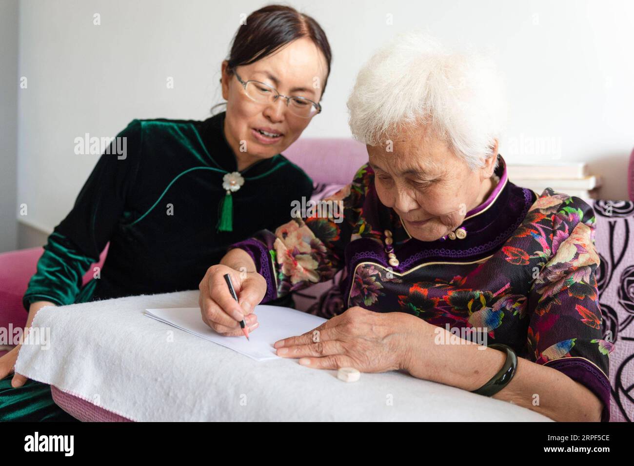 (190913) -- SUIHUA, 13. Sept. 2019 -- Jiang Shumei (R) praktiziert das Schreiben unter der Leitung ihrer Tochter zu Hause im Beilin-Bezirk der Stadt Suihua, nordöstliche chinesische Provinz Heilongjiang, 12. Sept. 2019. Jiang wurde 1937 geboren und war vor seinem 60. Lebensjahr Analphabet. Um Jiangs Not nach dem Tod ihres Mannes im Jahr 1996 bei einem Autounfall zu lindern, lehrte ihre Tochter Zhang Aailing seither die ältere Frau Lesen und Schreiben. Mit der Ermutigung ihrer Tochter versuchte Jiang, ein Buch zu schreiben. 2013 erschien Jiangs erstes Buch. Bis jetzt hat der 82-jährige Schriftsteller fünf Bücher veröffentlicht und gewonnen Stockfoto
