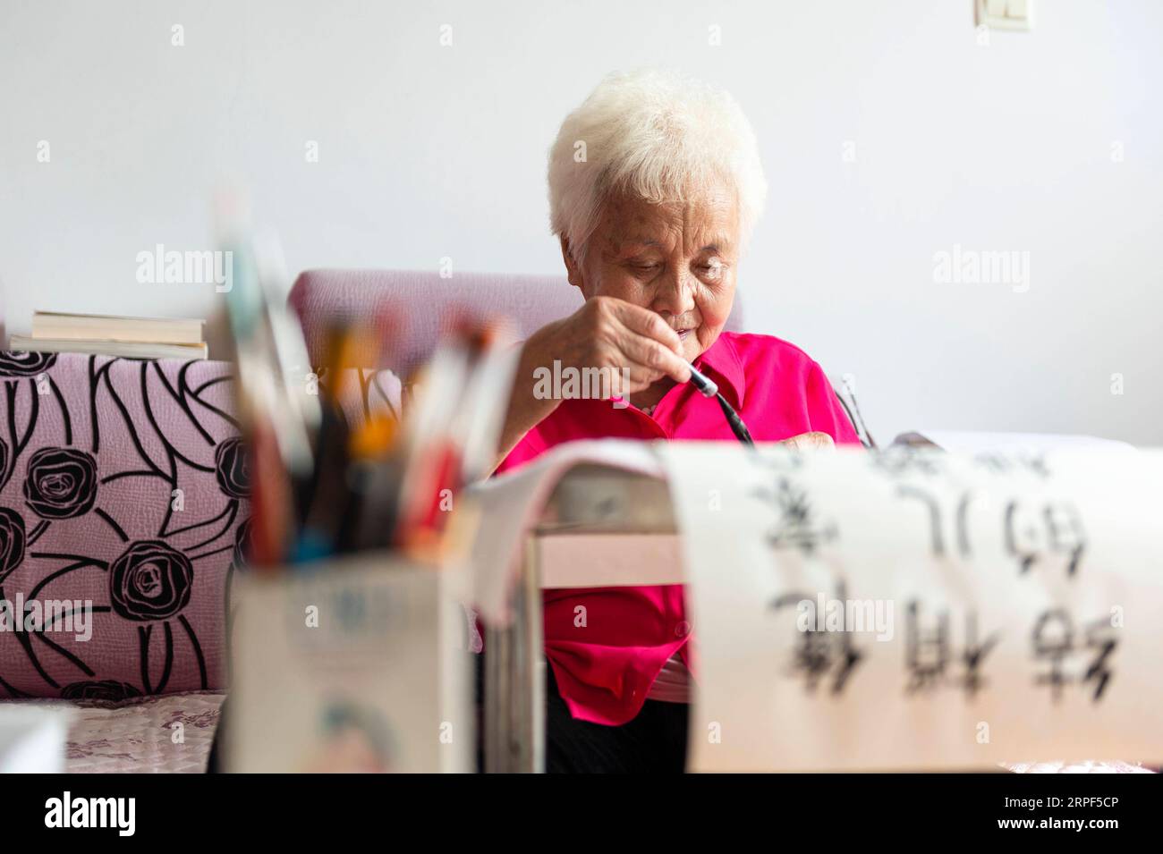 (190913) -- SUIHUA, 13. September 2019 -- Jiang Shumei praktiziert Kalligraphie zu Hause im Beilin-Bezirk der Stadt Suihua, nordöstliche chinesische Provinz Heilongjiang, 12. September 2019. Jiang wurde 1937 geboren und war vor seinem 60. Lebensjahr Analphabet. Um Jiangs Not nach dem Tod ihres Mannes im Jahr 1996 bei einem Autounfall zu lindern, lehrte ihre Tochter Zhang Aailing seither die ältere Frau Lesen und Schreiben. Mit der Ermutigung ihrer Tochter versuchte Jiang, ein Buch zu schreiben. 2013 erschien Jiangs erstes Buch. Bisher hat der 82-jährige Schriftsteller fünf Bücher veröffentlicht und mehrere Preise gewonnen. ) CHINA-HEILONGJI Stockfoto