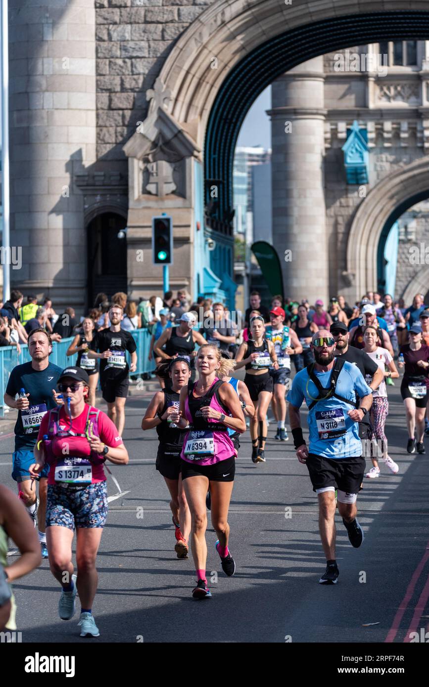 Lustige Läufer, die am Big Half, einem Halbmarathon, teilnehmen, der von London Marathon Events organisiert wird und in Tower Hamlets beginnt, die die Tower Bridge überqueren. Stockfoto