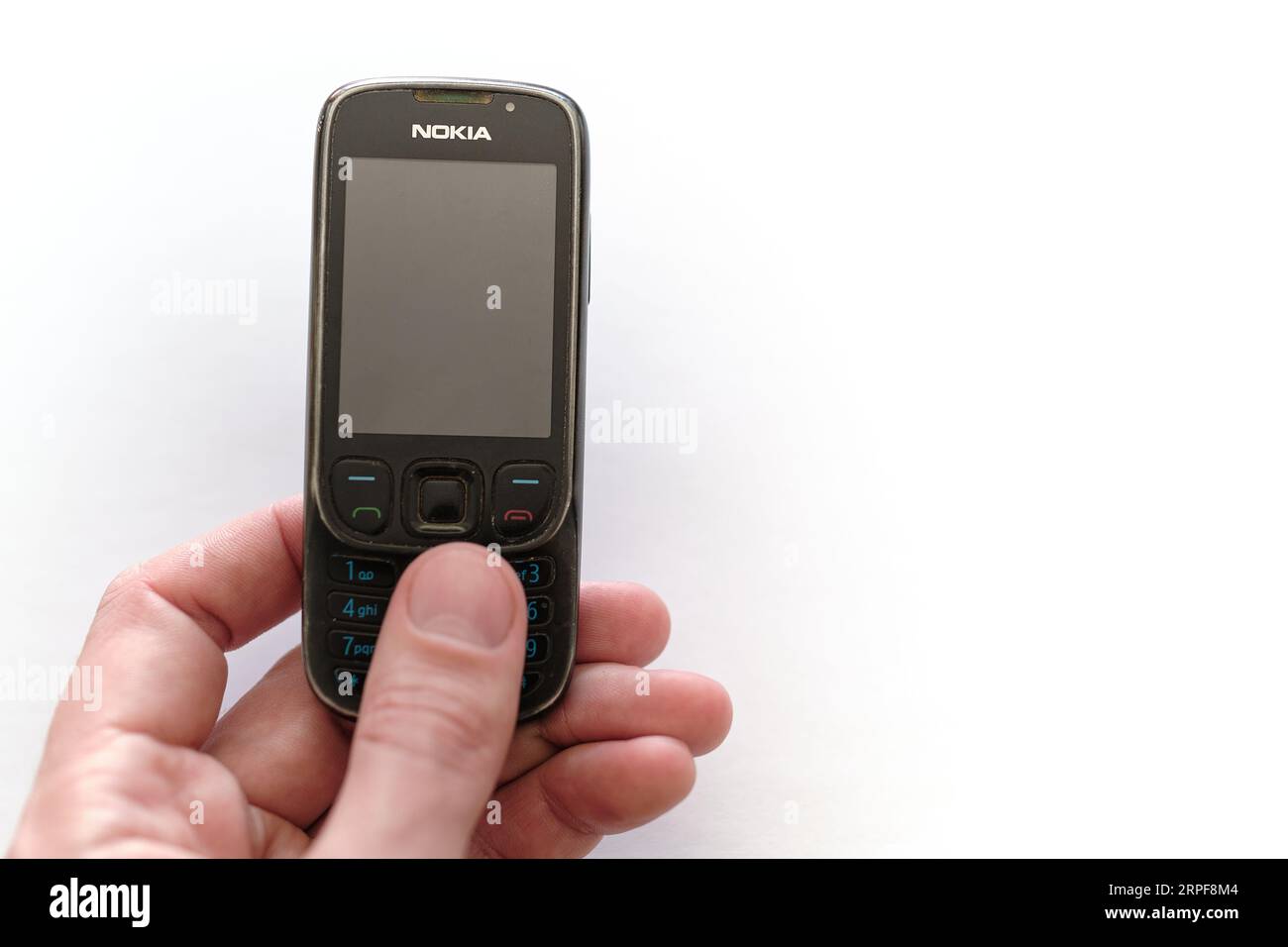 Altes gut gebrauchtes dummes Handy Nokia 6303 ci in einer Hand. Low-Tech-Konzept für Mobilgeräte. Veraltete Vintage-Technologie, die lange Zeit funktioniert. Stockfoto
