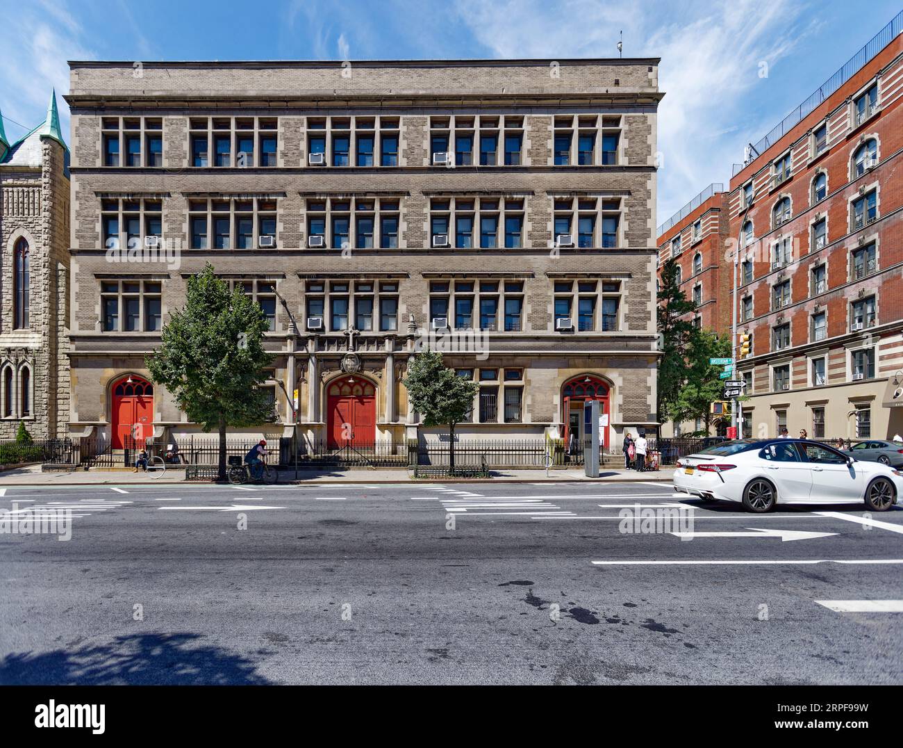 Upper West Side: School of the Holy Name of Jesus ist ein unsinniges, düsteres, graues Ziegel- und Steingebäude, das nur von bogenförmigen, rot bemalten Türen belebt wird. Stockfoto