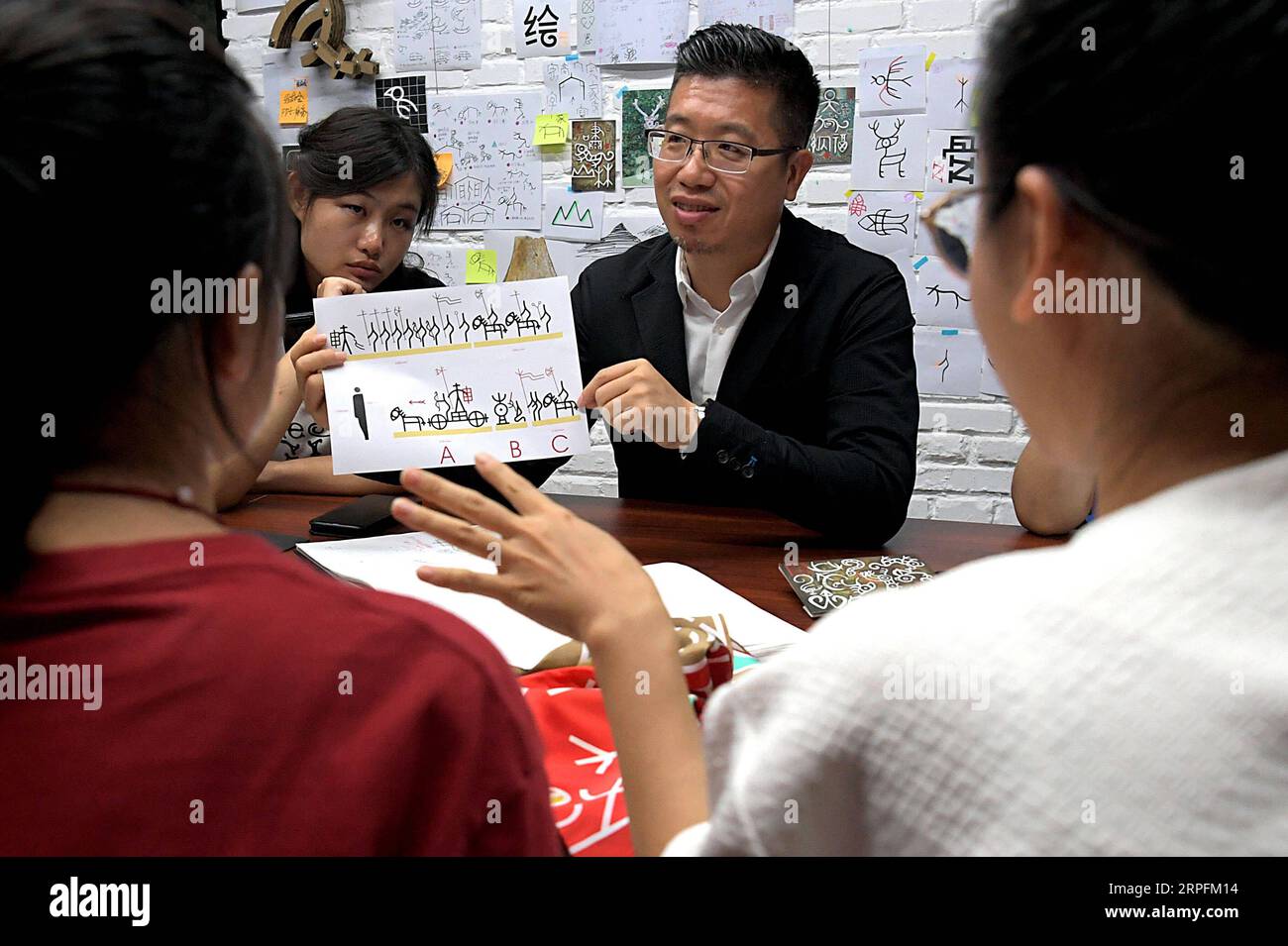 190927 -- PEKING, 27. September 2019 -- Chen Nan C und seine Teammitglieder diskutieren in seinem Atelier an der Tsinghua University in Peking, Hauptstadt Chinas, am 24. September 2019 über ein Design von oracle Bone Script. Mit einer Geschichte von mehr als 3.000 Jahren hat oracle Bone Script, die frühesten chinesischen Schreibinschriften, die auf Schildkrötenschalen und Tierscapulas gemeißelt wurden, dank der Bemühungen von Chen Nan moderne Bedeutungen mit einer neuen Reihe von Emojis erhalten. Chen, ein Professor an der Akademie der Künste und des Designs der Tsinghua Universität, widmet sich seit 1 dem Studium und dem Entwerfen von oracle Bone Script Stockfoto