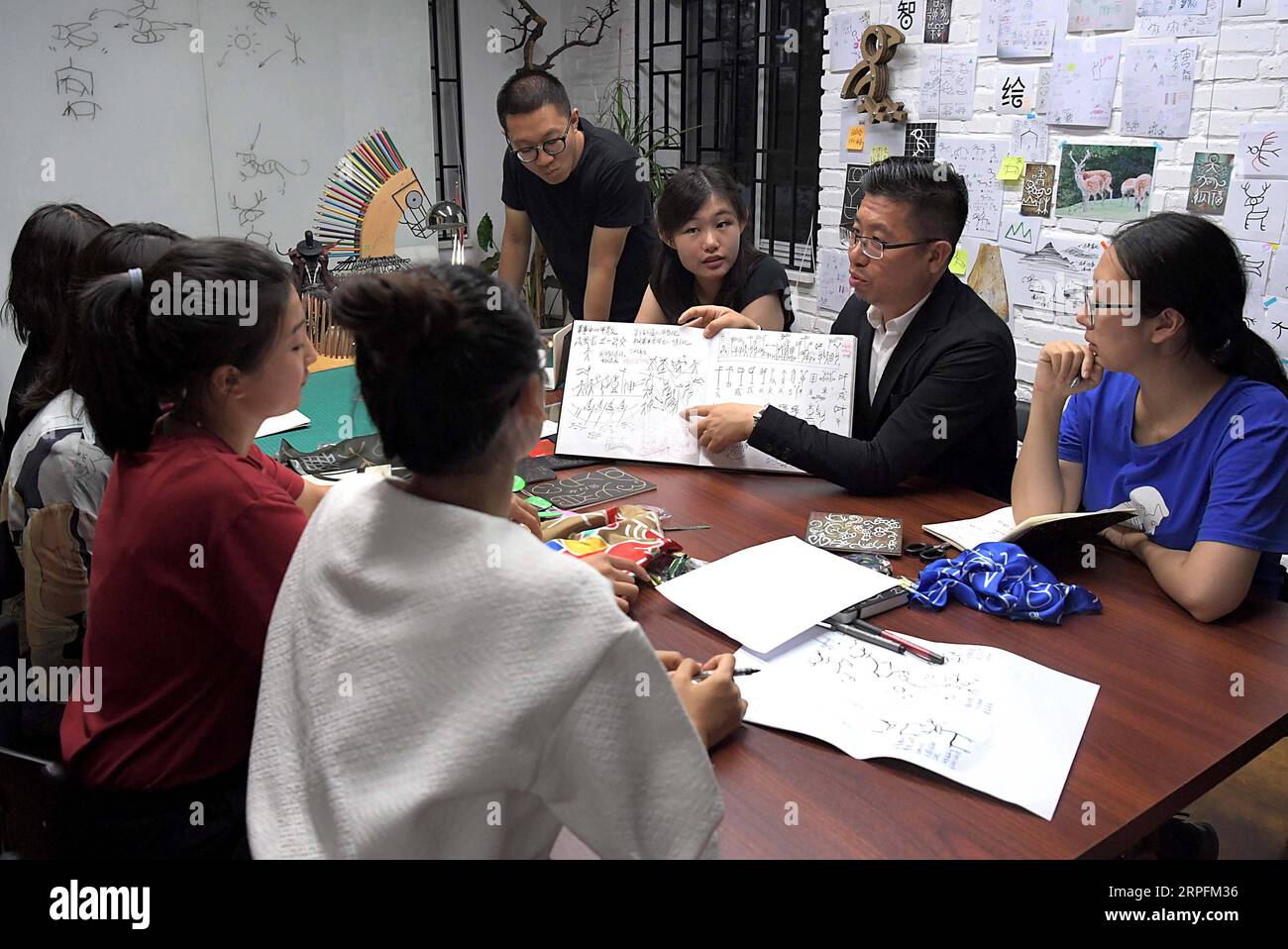 190927 -- PEKING, 27. September 2019 -- Chen Nan 2nd R, Back und seine Teammitglieder diskutieren ein Design-Schema von oracle Bone Skript in seinem Studio in der Tsinghua Universität in Peking, Hauptstadt von China, 24. September 2019. Mit einer Geschichte von mehr als 3.000 Jahren hat oracle Bone Script, die frühesten chinesischen Schreibinschriften, die auf Schildkrötenschalen und Tierscapulas gemeißelt wurden, dank der Bemühungen von Chen Nan moderne Bedeutungen mit einer neuen Reihe von Emojis erhalten. Chen, ein Professor an der Akademie der Künste und des Designs der Tsinghua Universität, hat sich dem Studium und dem Design von oracle Bone gewidmet Stockfoto
