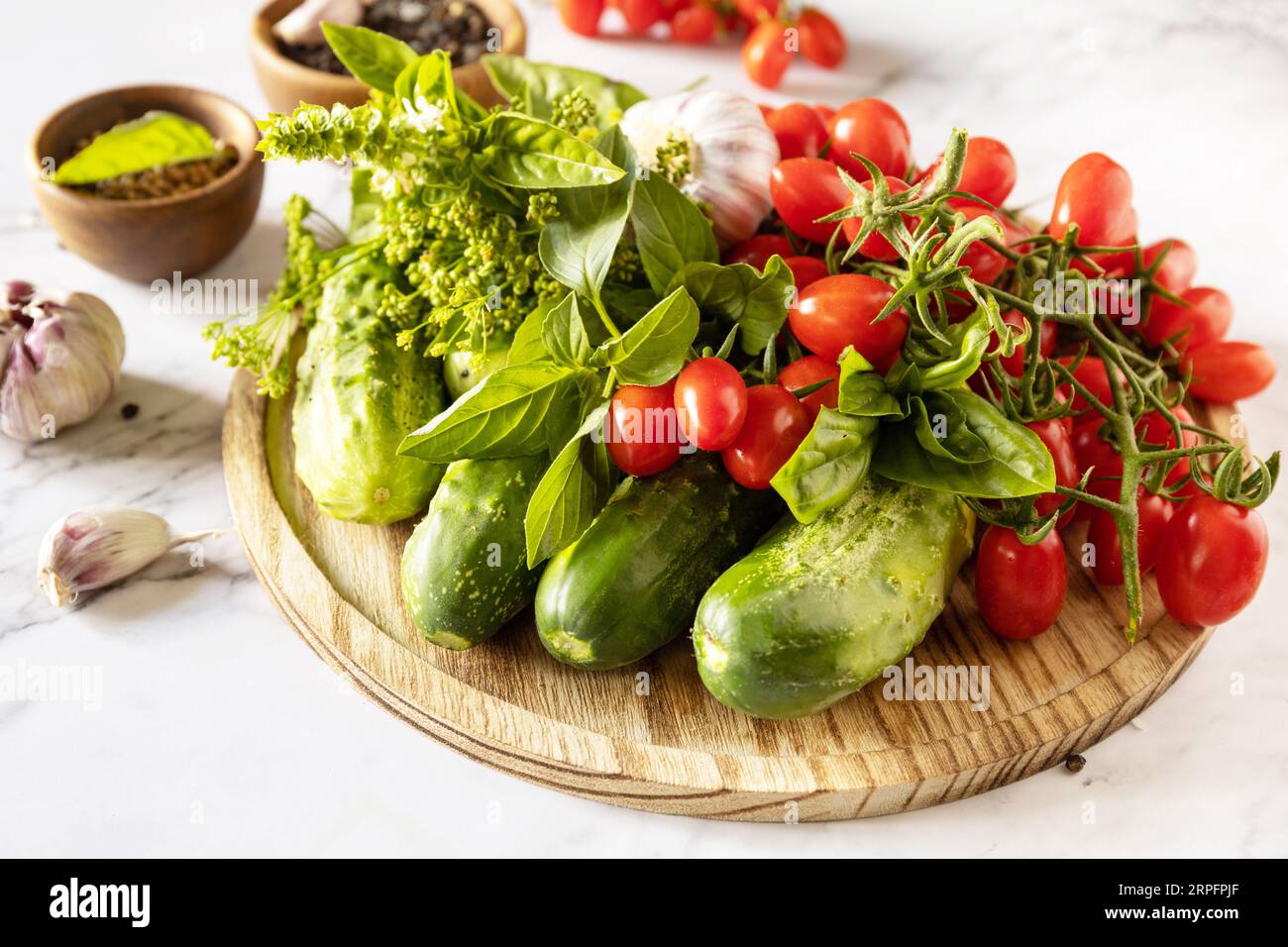 Frische Tomaten, Gurken und Gewürze für gesunde hausgemachte Gärung auf einem Marmortisch. Hauswirtschaft, Herbsternteerhaltung. Stockfoto