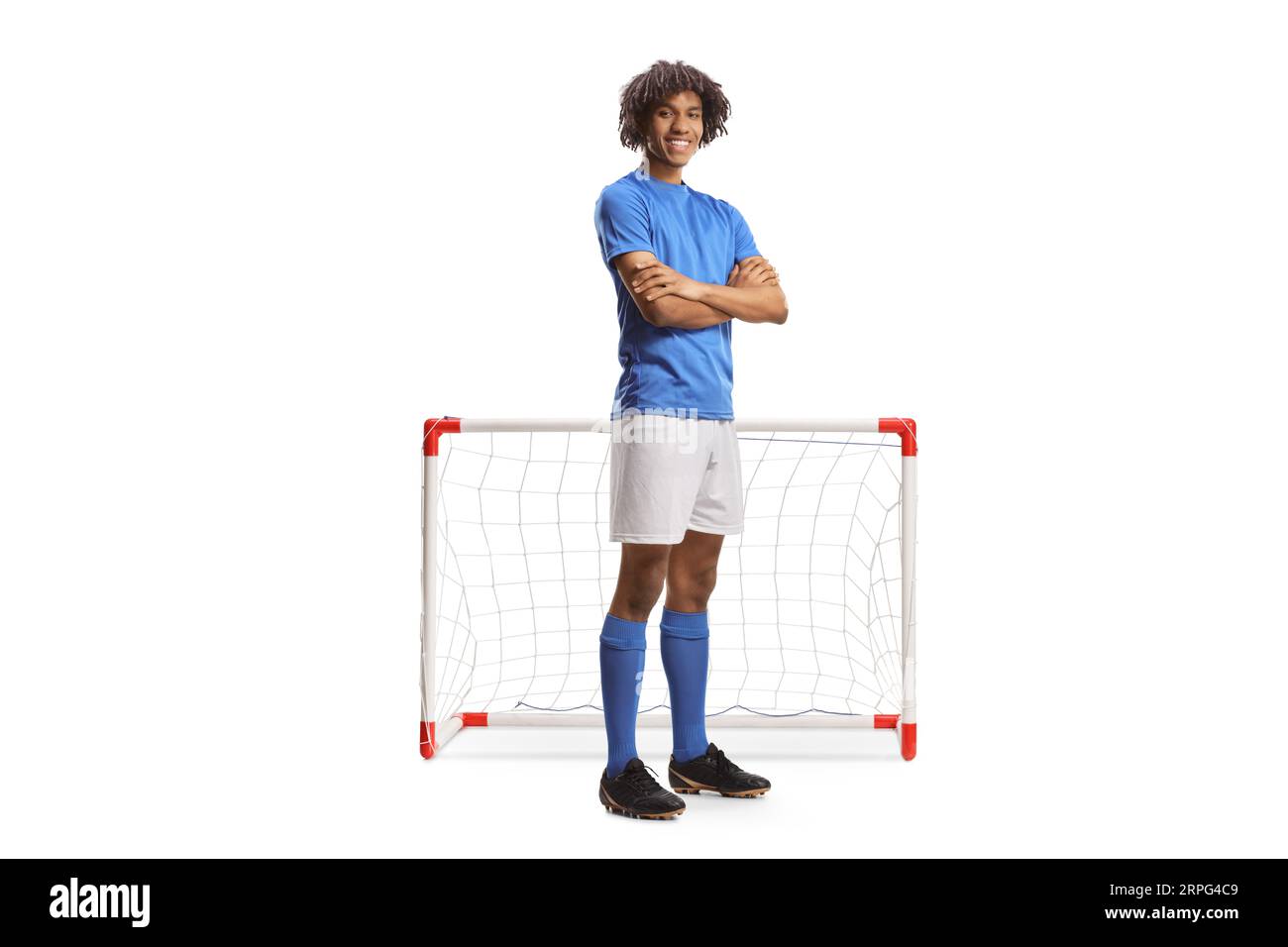 Portrait eines afroamerikanischen Fußballspielers in einem blauen Trikot, der mit gefalteten Armen vor einem auf weißem Backgro isolierten Minitor posiert Stockfoto