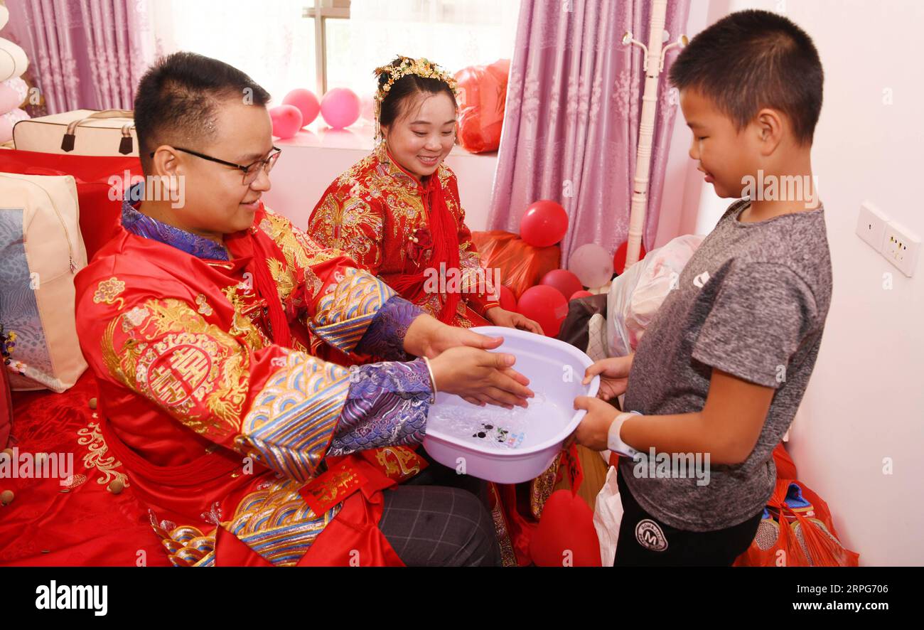 191005 -- TONGREN, 5. Oktober 2019 -- Bräutigam Pan Rongdong und Braut Tan Lifei waschen sich die Hände, um an ihrem Hochzeitstag in ihrem Haus im Bezirk Bijiang der Stadt Tongren, Provinz Guizhou im Südwesten Chinas, am 4. Oktober 2019 für Glück zu beten. Pan Rongdong ist ein Mitarbeiter des Gesundheitszentrums für Mütter und Kinder im Bezirk Wanshan in Tongren. Im September 2017, als Pan in das Dorf Wengbei in der Gemeinde Aozhai in Wanshan geschickt wurde, um an der Armutsbekämpfung zu arbeiten, lernte er Tan Lifei kennen, den Direktor der Armutsbekämpfungsstation für Aozhai. Während ihrer Arbeit an gezielten p Stockfoto