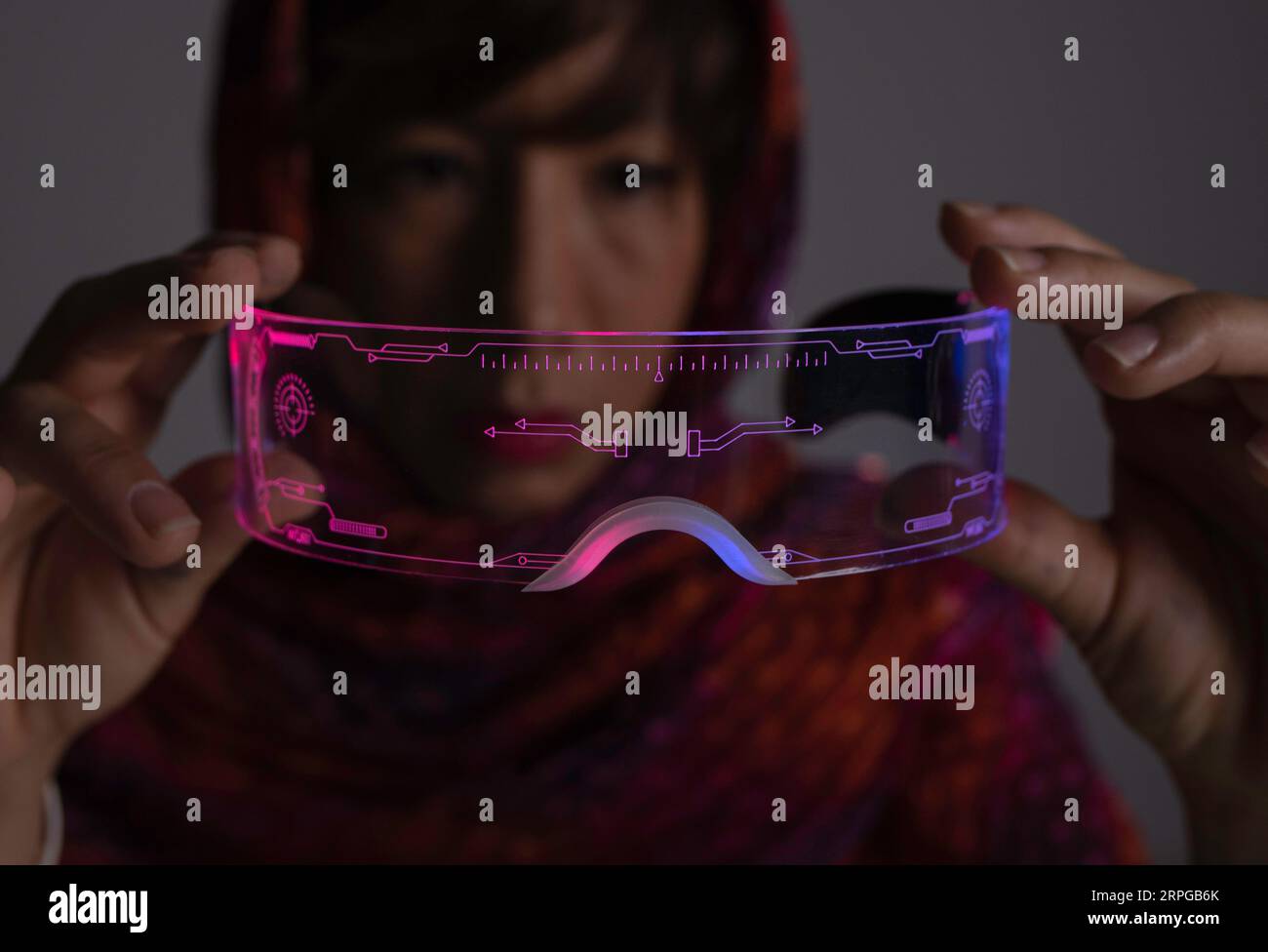 Asiatisches Mädchen, das futuristische Leuchtgläser betrachtet Stockfoto