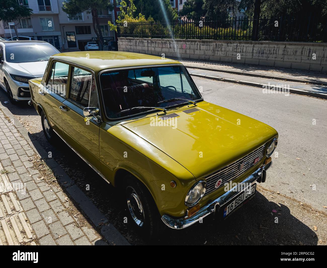 Gelber Oldtimer auf der Straße geparkt, perfekter Zustand, klassischer FIAT 124. Hochwertige Fotos Stockfoto