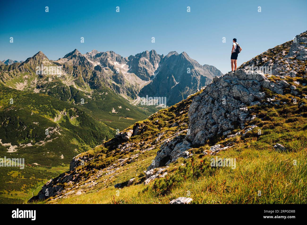 Ein jugendlicher Entdecker taucht in die unberührte Landschaft der Belianske Tatra ein, wobei die ikonische hohe Tatra den Horizont in der Ferne ziert Stockfoto