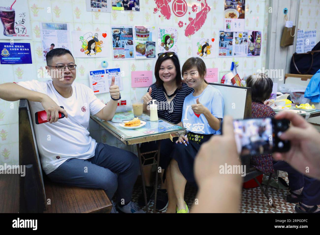 191012 -- HONGKONG, 12. Oktober 2019 -- Kate Lee 3rd L posiert für ein Foto mit Kunden in ihrem Teestaurant in Kowloon, südchinesisches Hongkong, 10. Oktober 2019. Eingebettet in den labyrinthartigen Fischmarkt des ruhigen Fischerdorfes Lei Yue Mun in Hong Kong, ist ein kleines, gemütliches Teestaurant unerwartet zu einem Leuchtturm des Mutes für gewöhnliche Menschen in Hongkong geworden, die Frieden inmitten des Chaos der letzten Zeit suchen. Nachdem sie Ende Juni Bilder postete, die die Polizei Hongkongs gegen einige radikale Demonstranten unterstützten, fand Kate Lee, die Besitzerin des Teestaurants, dass ihr Gewissen ihrer Familie einen hohen Tribut forderte Stockfoto