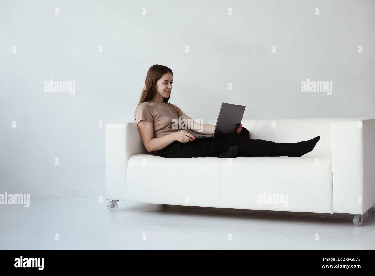 Junge Frau sitzt auf einem Sofa mit Laptop. Konzept Online-Sitzung mit einem Psychologen Stockfoto