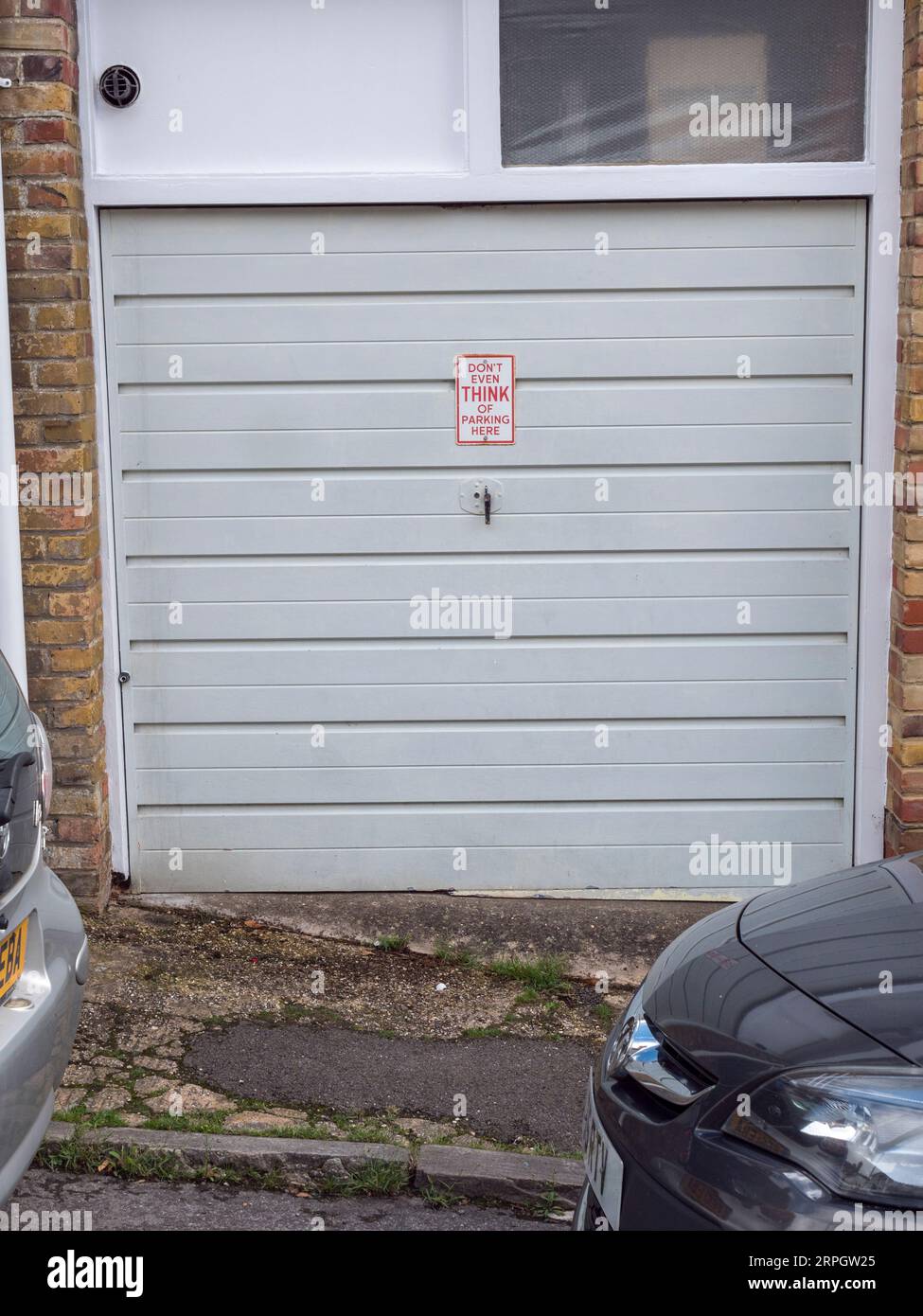 Komisch und ignoriert "DENKEN SIE nicht einmal an Parken hier" Schild auf einer Autogarage in einer Wohnstraße in Arundel, West Sussex, Großbritannien. Stockfoto