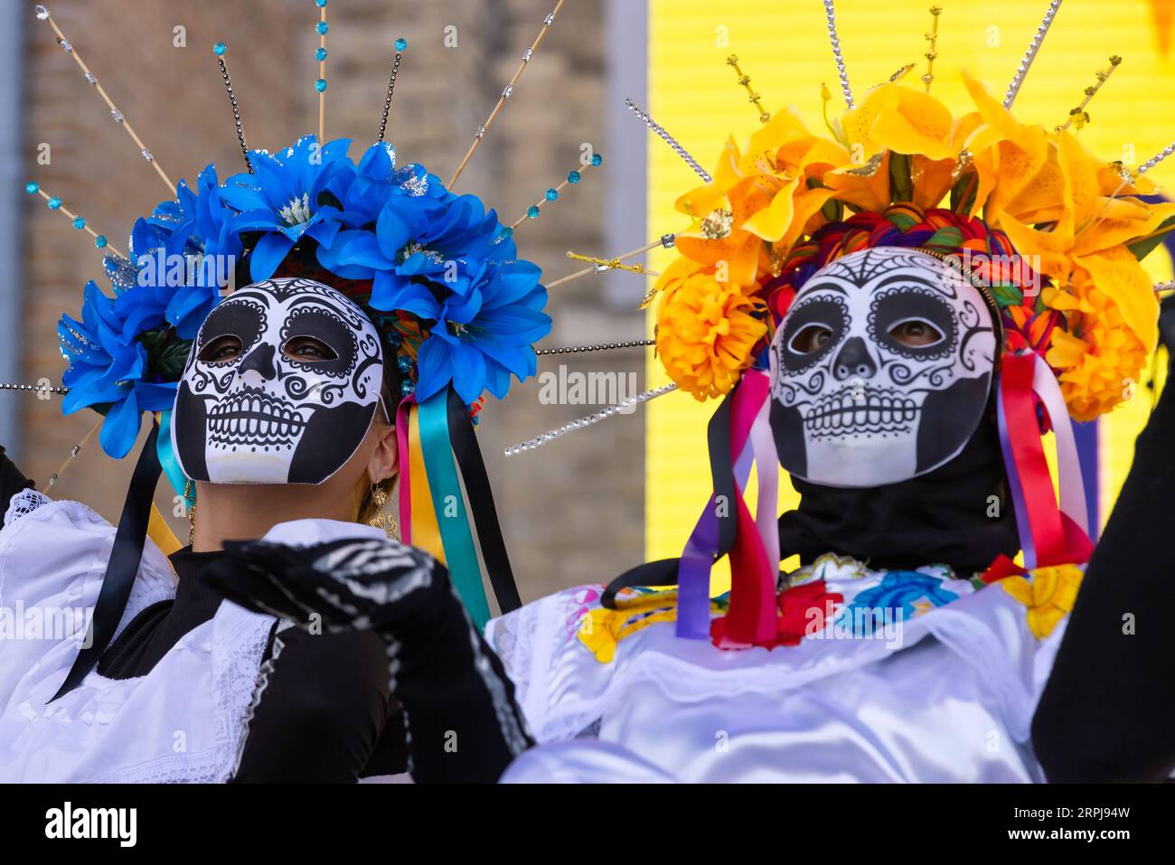 Porträt von maskierten Frauen, die an den Feierlichkeiten von Dia de Los Muertos teilnehmen, in traditionellen Kostümen und Zuckerschädelmasken Stockfoto