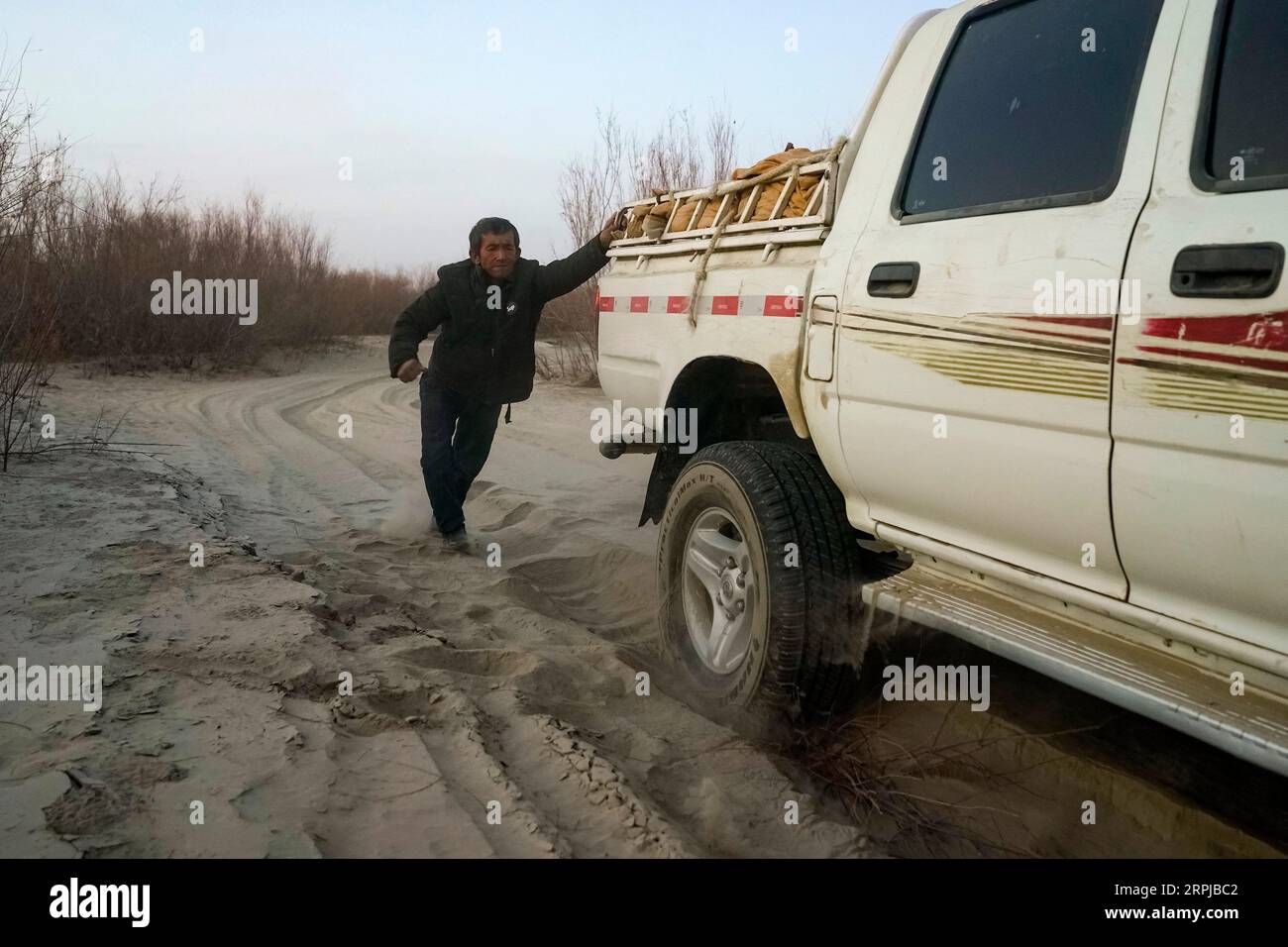 191204 -- ÜRÜMQI, 4. Dezember 2019 -- Imin hilft, das gestrandete Fahrzeug auf dem Weg zum Umzugsgebiet für Darya Boyi Stadt im Yutian County, Nordwestchinas autonome Region Xinjiang Uygur, 17. November 2019 zu schieben. Bevor er am 17. Und 18. November dieses Jahres in die neue Siedlung zog, lag das Haus des Schafhirten Imin im Herzen der Taklimakan-Wüste, der zweitgrößten Sandwüste der Welt. Seit Hunderten von Jahren siedeln sich Imins Vorfahren am Keriya River an, der von Süden nach Norden in das Herz endloser Sanddünen fließt, sich wie Finger verzweigt und die Quelle bildet Stockfoto