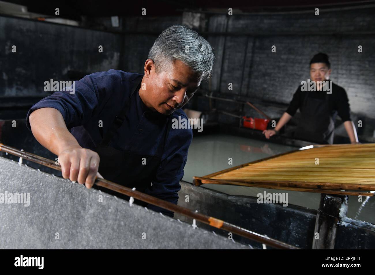 191209 -- JINGXIAN, 9. Dezember 2019 -- Cao Jianqin und sein Sohn Cao Li machen Xuan-Papier in der Zijinlou Xuan-Papierfabrik im Jingxian County, Stadt Xuancheng in der ostchinesischen Provinz Anhui, 8. November 2019. Xuan-Papier, traditionelles chinesisches Papier, das im Jingxian County in der Stadt Xuancheng hergestellt wird, hat eine Geschichte von mehr als 1.000 Jahren. Bei mehr als 100 Verfahren kostet die Herstellung des Papiers mindestens ein Jahr, um das Material in das Endprodukt zu verwandeln. Das Papier ist bekannt für seine ausgezeichnete Handwerkskunst, seine feine Qualität und seine lange Erhaltungszeit und wird von chinesischen Künstlern und Kalligraphen geliebt und wird PA genannt Stockfoto