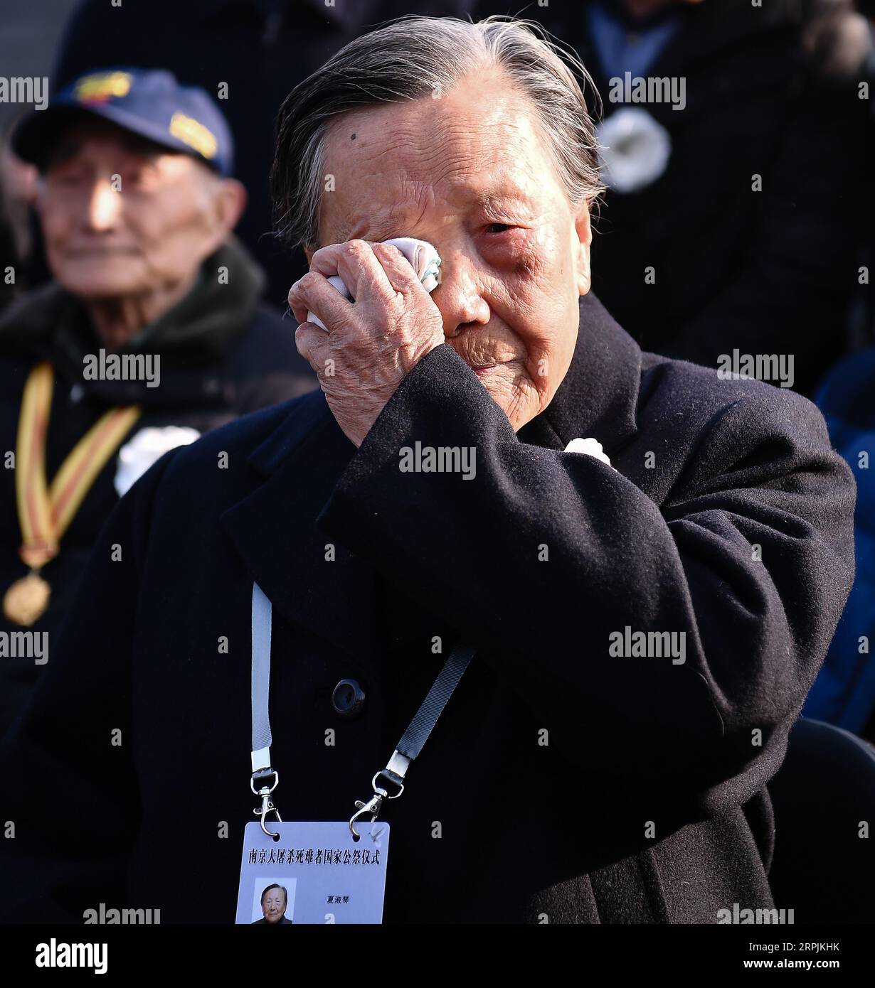 191213 -- NANJING, 13. Dezember 2019 -- der Überlebende des Massakers von Nanjing Xia Shuqin nimmt an einer nationalen Gedenkfeier für die Opfer des Massakers von Nanjing in der Gedenkhalle der Opfer des Massakers von Nanjing durch japanische Invasoren in Nanjing, der Hauptstadt der ostchinesischen Provinz Jiangsu, am 13. Dezember 2019 Teil. Vor der schwarzen Menschenmenge flog Chinas Nationalflagge am Halbmast, als die Nation am Freitag eine Gedenkfeier hielt, um die 300.000 Opfer des Massakers von Nanjing zu trauern. Bei der sechsten nationalen Gedenkfeier in Nanjing nahmen mehr als 8.000 Menschen aus allen Gesellschaftsschichten an einer weißen Blume Teil. Stockfoto