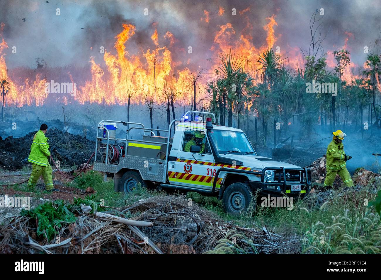 Rettungsdienste Feuerwehrmänner, die arbeiten, um einen Fluchtort zu kontrollieren kontrollierte Gefahrenreduzierung brennen in der Buschland am Stadtrand von Darwin. Stockfoto