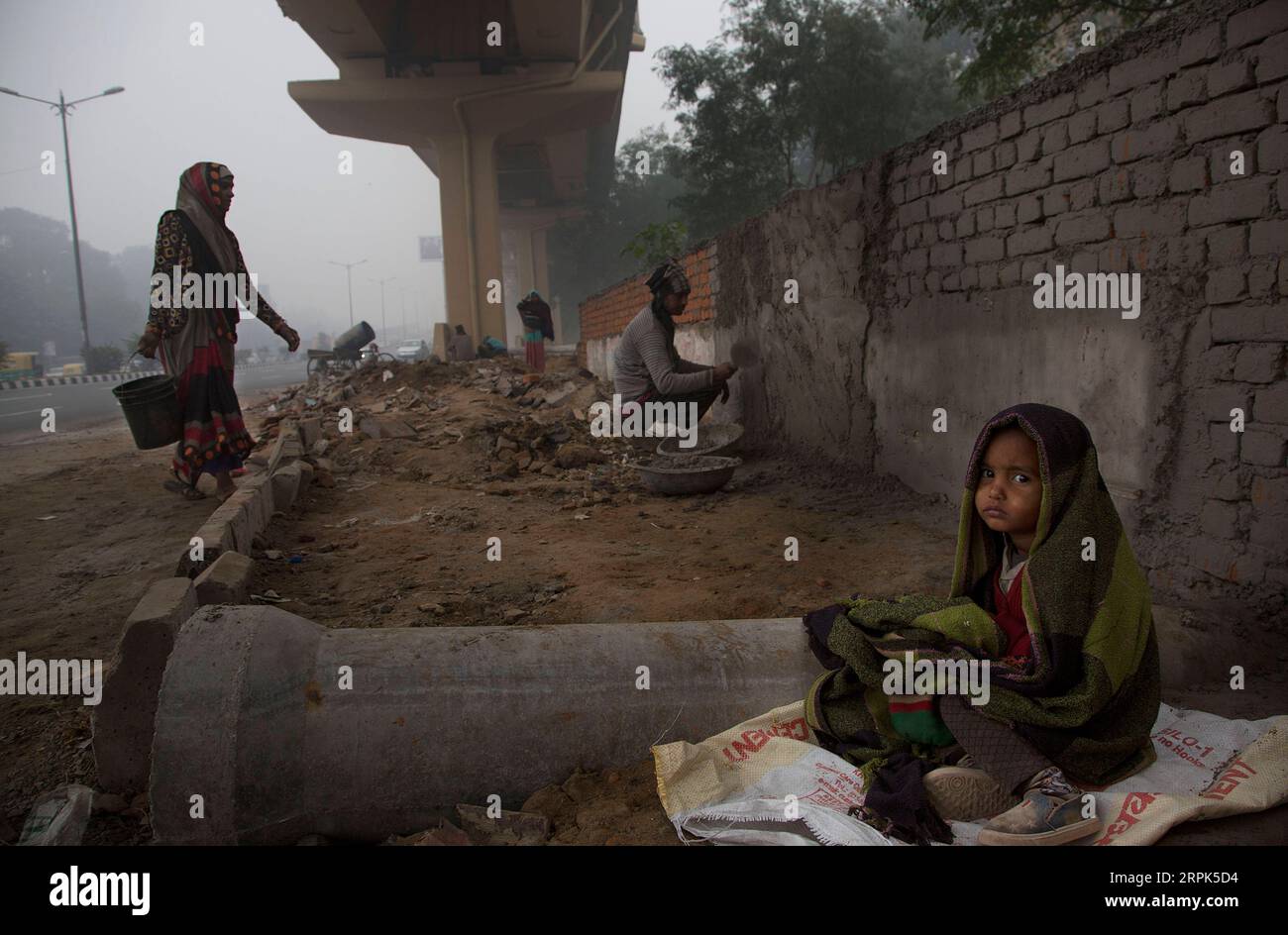 191230 -- NEW DELHI, 30. Dezember 2019 -- Ein Kind wird in einen Schal gehüllt, während die Eltern auf einer Baustelle unter dichtem Nebel in New Delhi arbeiten, 30. Dezember 2019. Eine dichte Nebeldecke bedeckte die indische Hauptstadt New Delhi und die Außenbezirke am Montagmorgen, was zu Störungen im Luft- und Schienenverkehr führte, sagten Beamte. Foto von /Xinhua INDIA-NEW DELHI-WETTER-DICHTER NEBEL JavedxDar PUBLICATIONxNOTxINxCHN Stockfoto