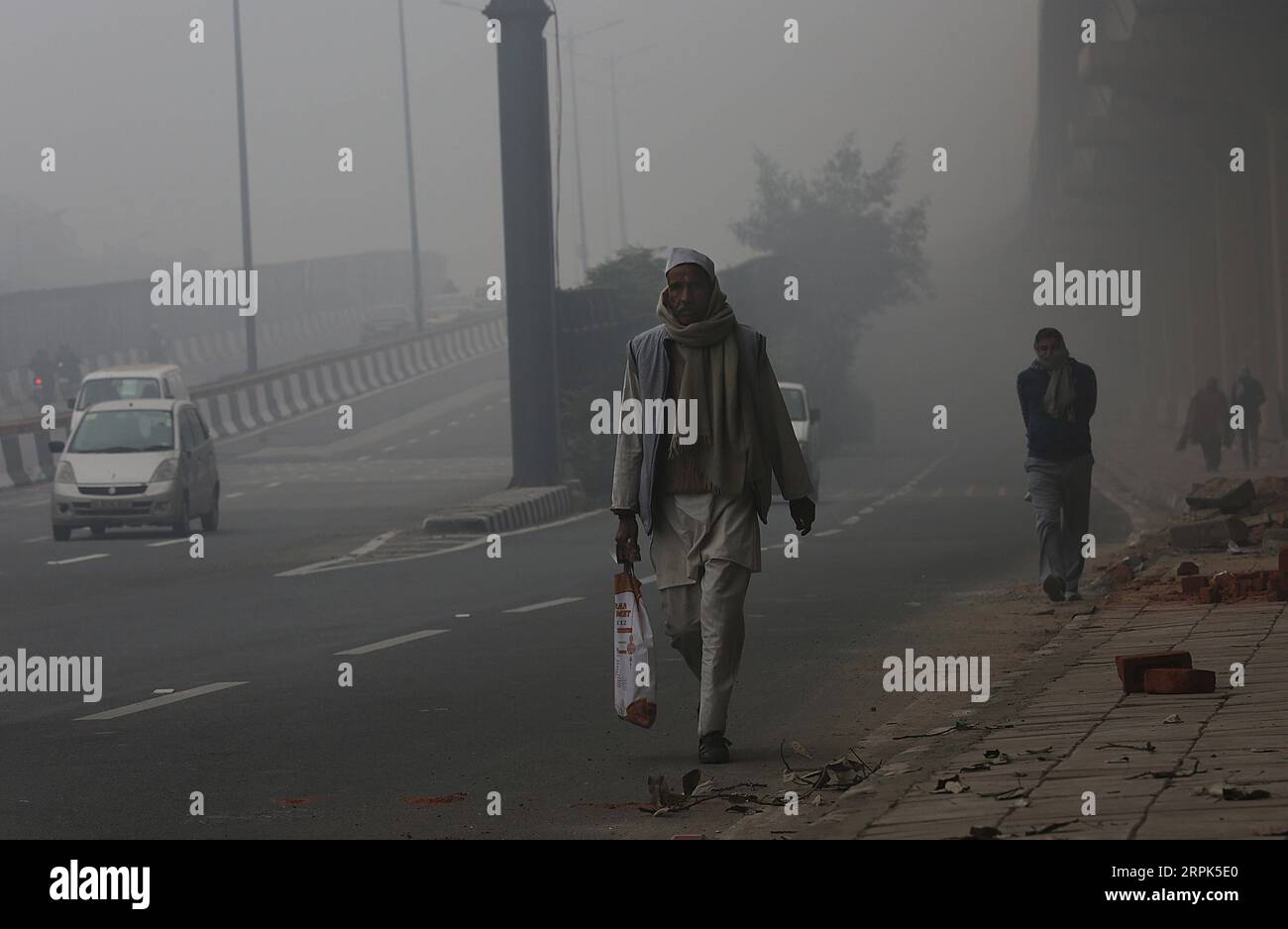 191230 -- NEW DELHI, 30. Dezember 2019 -- Menschen gehen auf einer Straße in dichtem Nebel in New Delhi, 30. Dezember 2019. Eine dichte Nebeldecke bedeckte die indische Hauptstadt New Delhi und die Außenbezirke am Montagmorgen, was zu Störungen im Luft- und Schienenverkehr führte, sagten Beamte. Foto von /Xinhua INDIA-NEW DELHI-WETTER-DICHTER NEBEL JavedxDar PUBLICATIONxNOTxINxCHN Stockfoto
