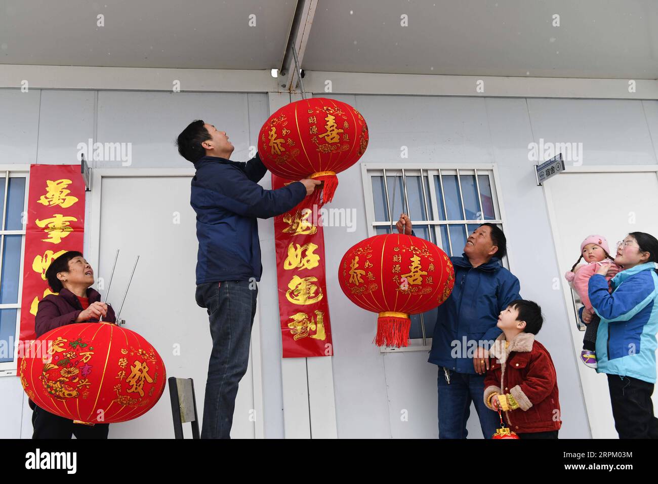 200122 -- CHUZHOU, 22. Januar 2020 -- Jiang Hao 2nd L, Chefingenieur des Phase-1-Baues der Intercity-Eisenbahn Chuzhou-Nanjing, hängt am 21. Januar 2020 eine Laterne am Lager in der Nähe der Baustelle in Chuzhou, ostchinesische Provinz Anhui. Das Intercity-Eisenbahnprojekt Chuzhou-Nanjing wird von China Tiesiju Civil Engineering Group Co., Ltd. In der ersten Phase durchgeführt Aufgrund der Arbeitsanforderungen können Jiang Hao, ein Chefingenieur des Projekts, und seine Frau Ke Jinglan, die auch hier für dasselbe Projekt gearbeitet hat, nicht nach Hause in der zentralchinesischen Provinz Hunan zurückkehren, um sich zu vereinigen Stockfoto