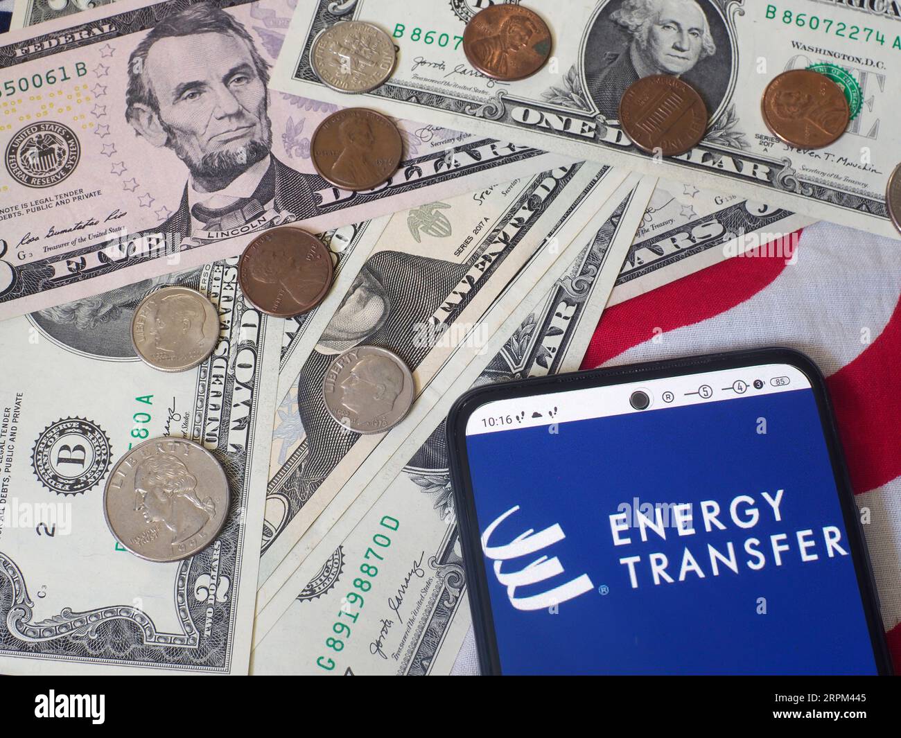 In dieser Abbildung wird das Energy Transfer LP-Logo auf einem Smartphone und US-Banknoten und -Münzen im Hintergrund angezeigt. Stockfoto