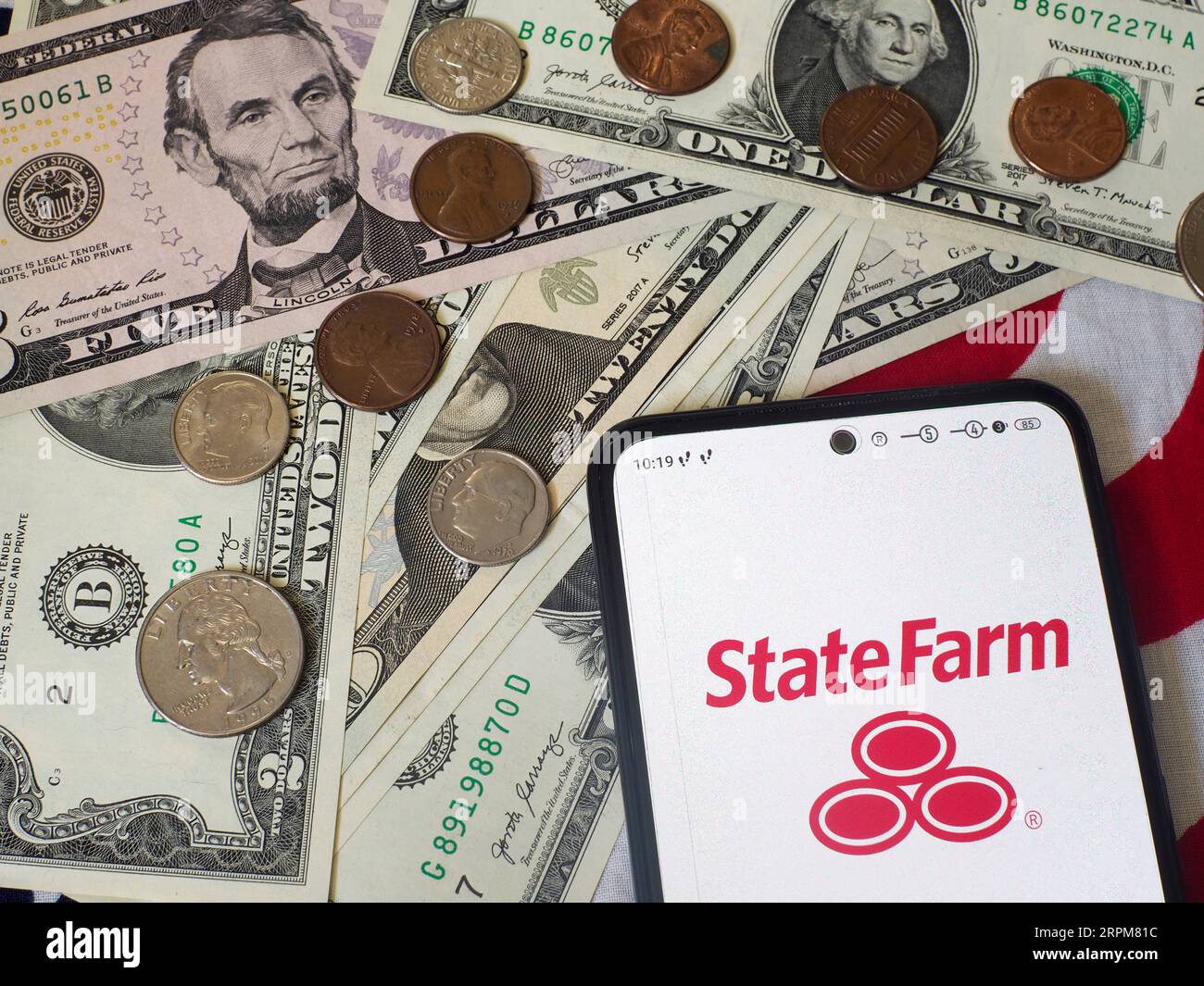 In dieser Abbildung wird das Logo der State Farm Mutual Automobile Insurance Company auf einem Smartphone und auf US-Banknoten und -Münzen angezeigt Stockfoto