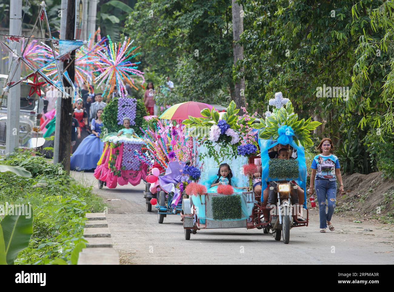 Kinder, die in einem dekorierten Dreirad zum religiös-historischen Schönheitswettbewerb Flores de Mayo, zur rituellen Kulturparade Santacruzan und zum philippinischen Festival paraden Stockfoto