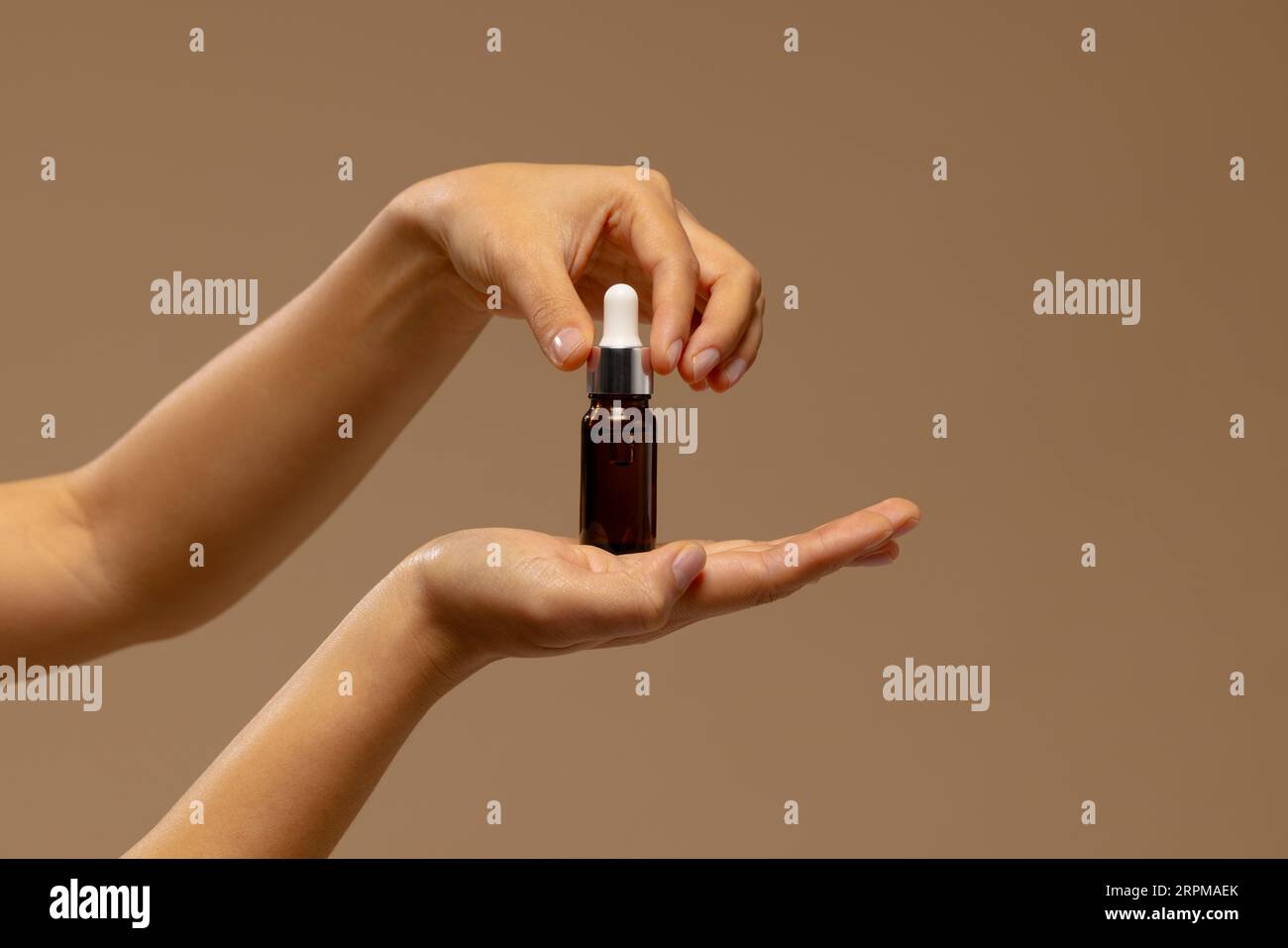 Hand einer asiatischen Frau, die Tropfflasche des Hauttonikums mit Kopierraum hält Stockfoto