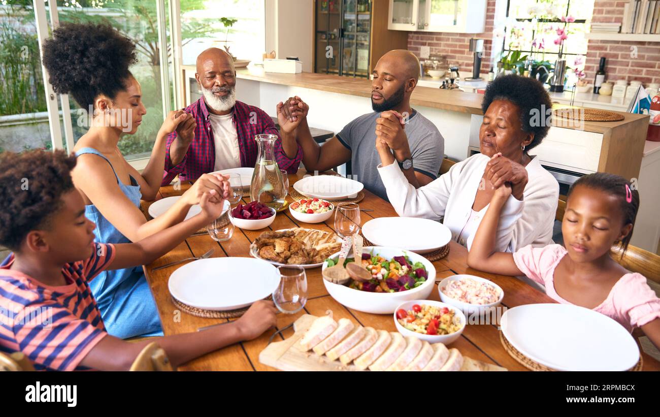 Die Familie Der Mehrgenerationen Ist Zu Hause Und Spricht Vor Dem Essen Ein Gebet Stockfoto