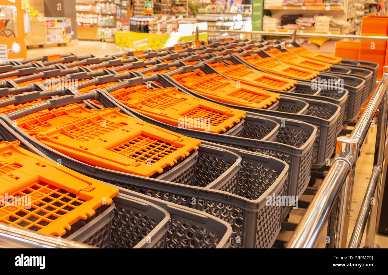 Einkaufswagen im Einkaufszentrum. Marktplatz. Gestapelte Einkaufswagen. Einzelhandel. Einkaufswagen mit orangefarbenem Griff. Innenausstattung des Supermarkts. Stockfoto