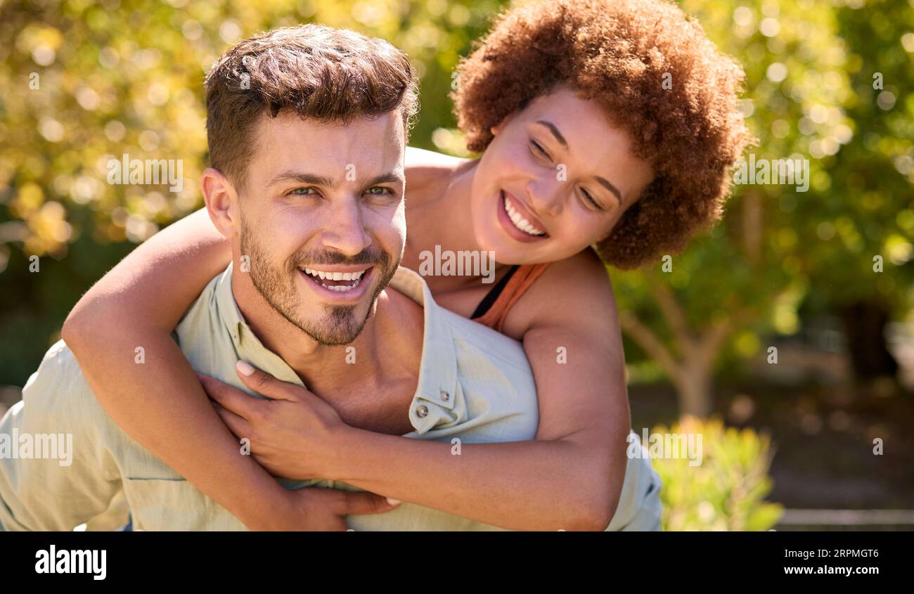 Porträt Eines Liebevollen Multi-Racial-Paares Mit Mann, Der Im Garten Eine Frau Mit Huckepack Gibt Stockfoto