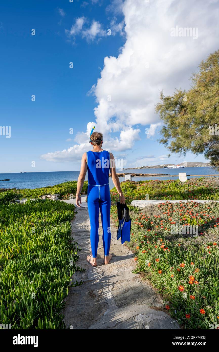 Junger Mann mit Taucherbrille, Schnorchel, blauen Flossen und blauem Neoprenanzug, Paros, Kykladen, Griechenland Stockfoto
