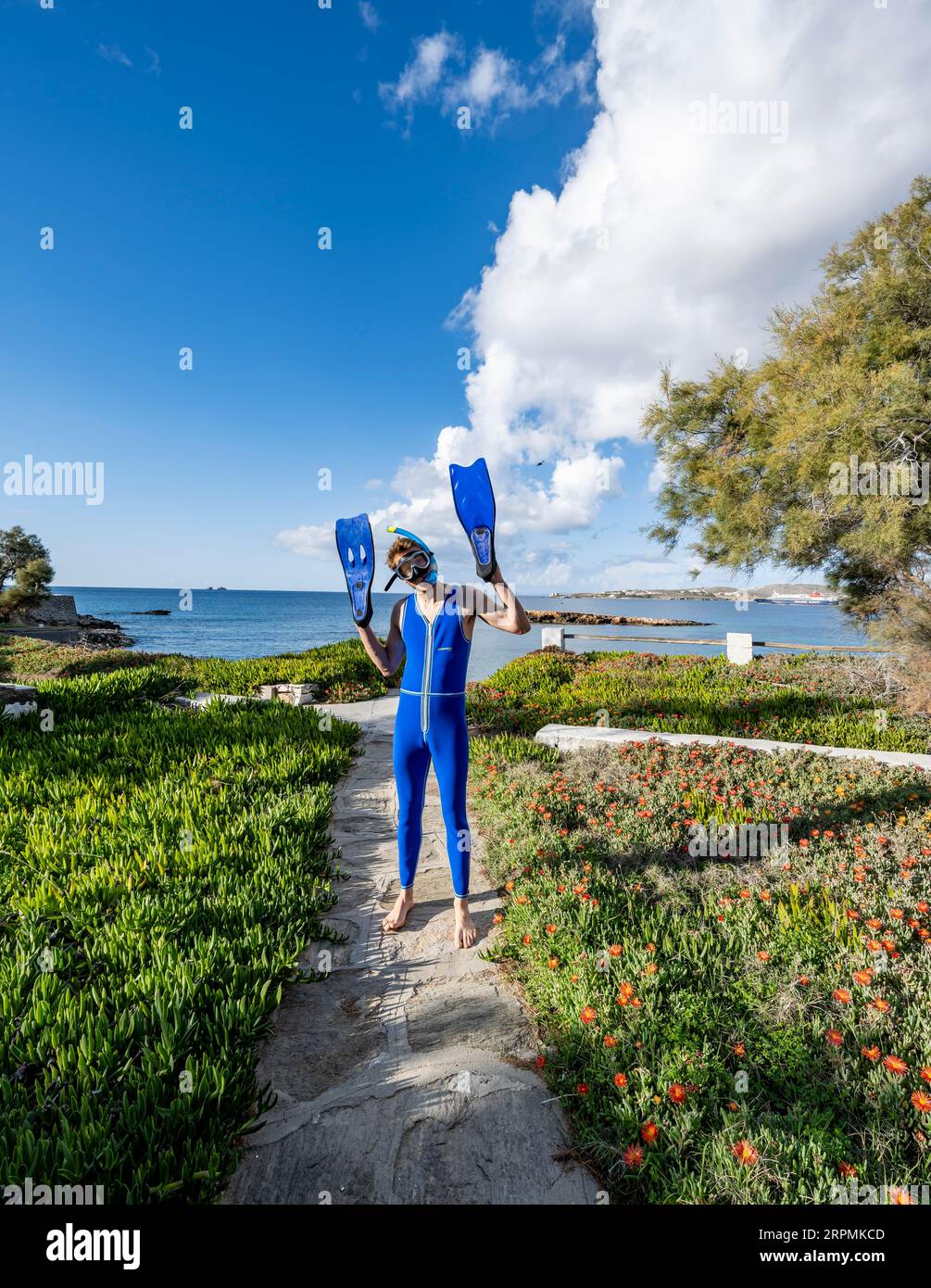 Junger Mann mit Taucherbrille, Schnorchel, blauen Flossen an den Händen und blauem Neoprenanzug, lustig, Paros, Kykladen, Griechenland Stockfoto